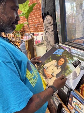 Person reading a magazine with a woman on the cover, inside a bookstore or library, with a cat nearby.