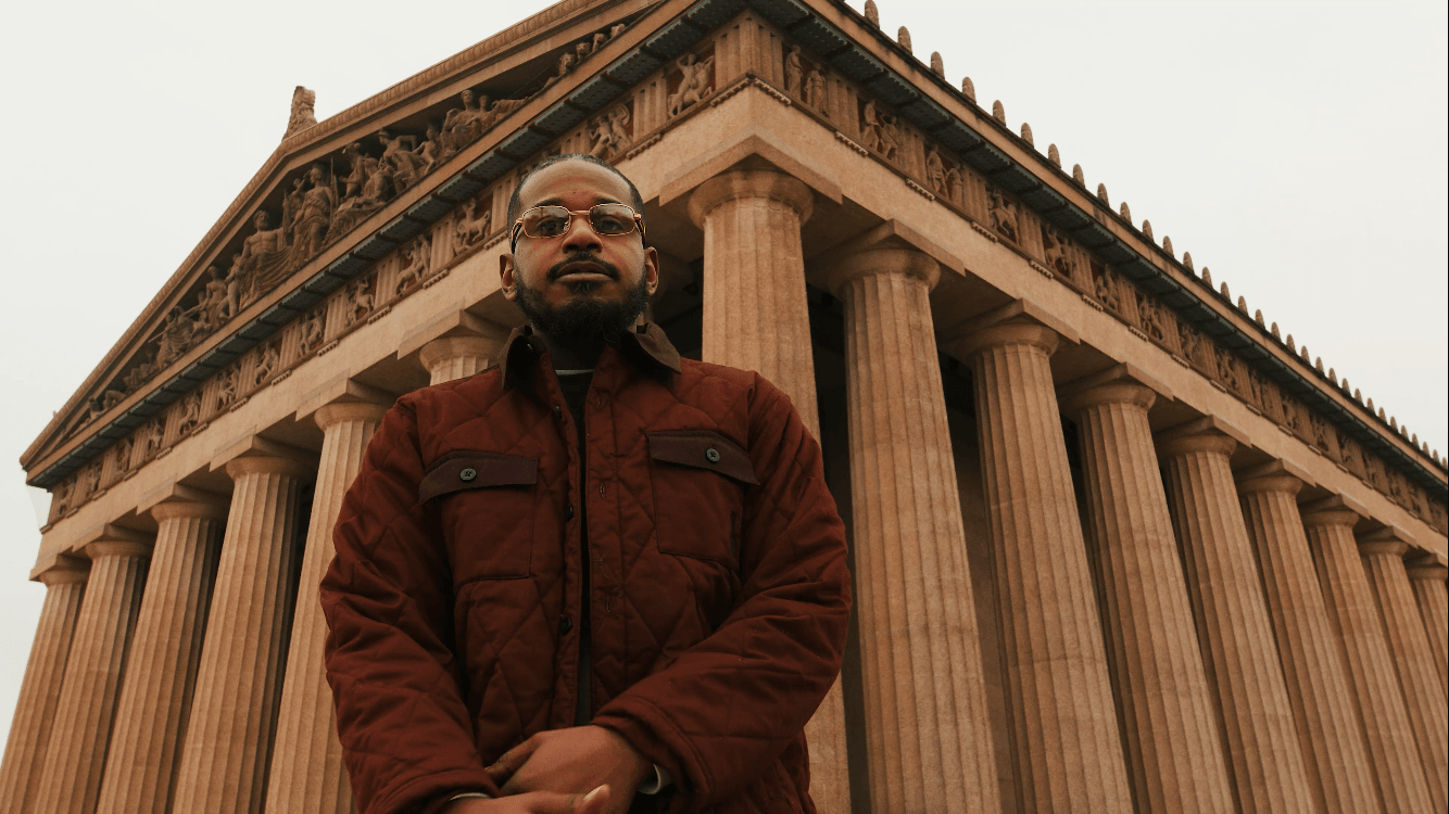 Man standing in front of a large classical building with tall columns and detailed architecture.
