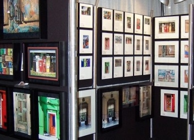 Display of framed artwork and photographs on black walls in an art gallery.