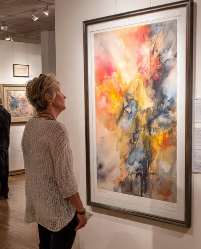 Woman observing a large abstract painting with vibrant colors in an art gallery.