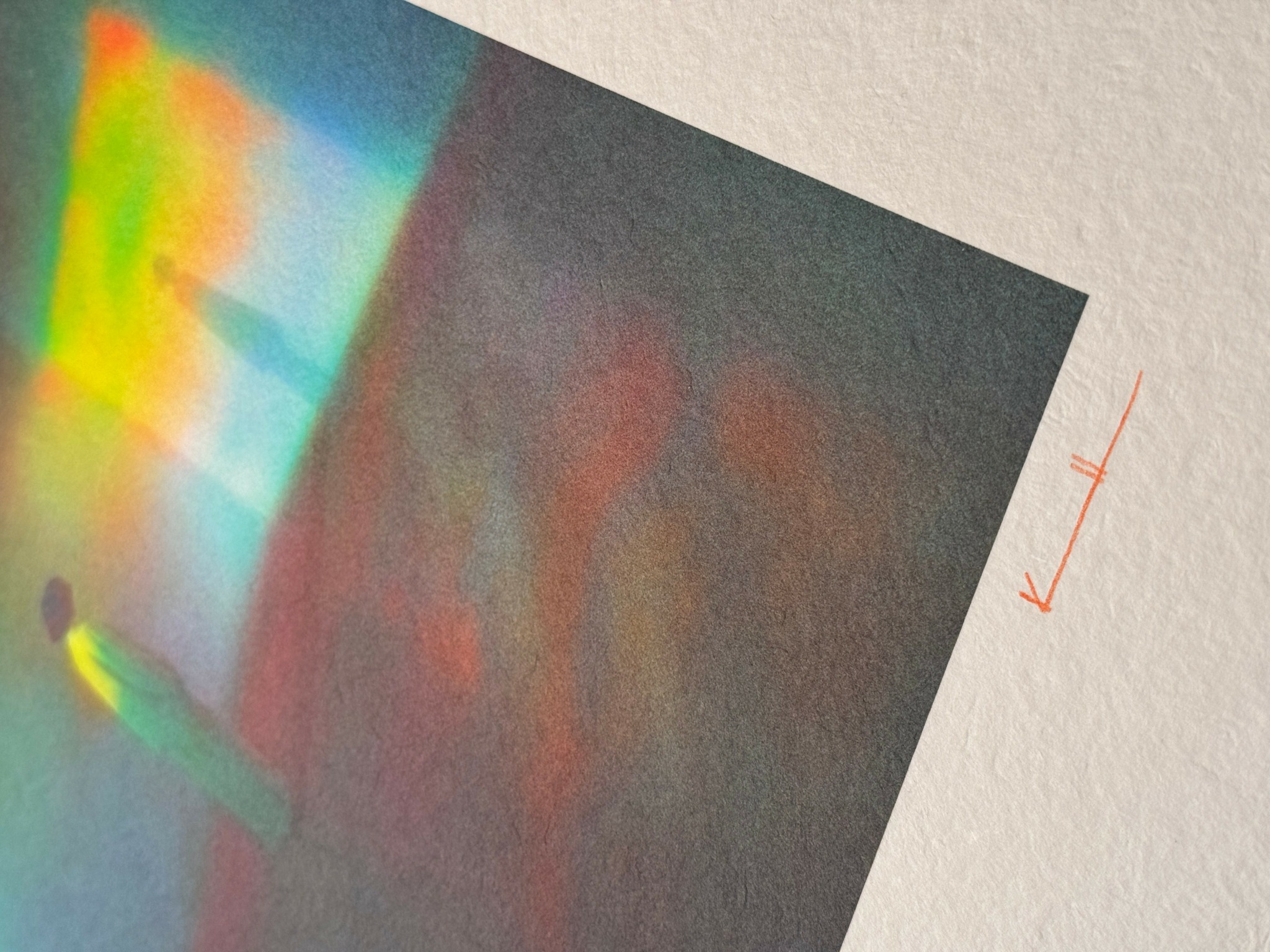 Colorful abstract pattern with rainbow-like hues on a textured surface.