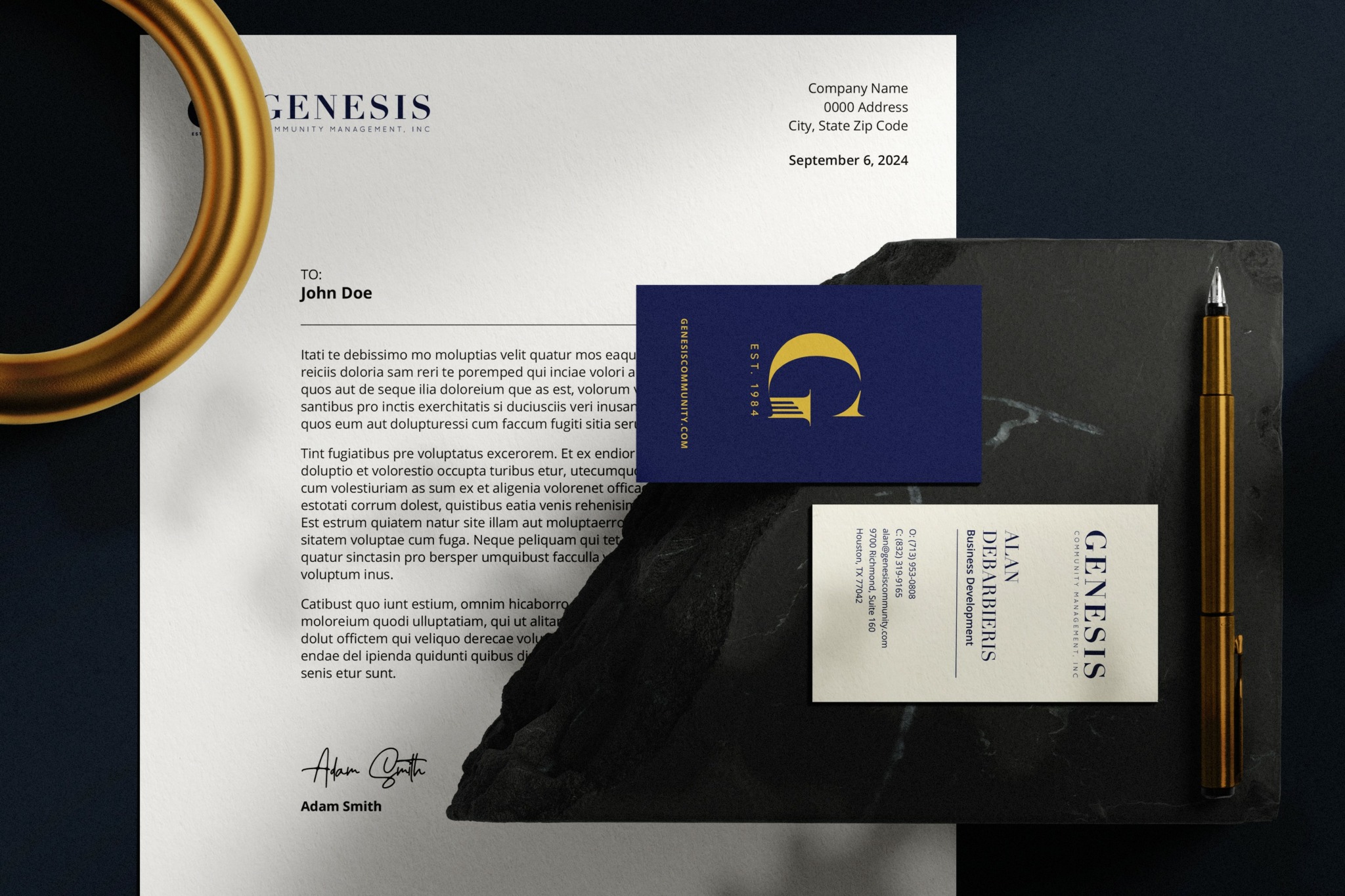 Letter on black stone with business card and pen, gold ring on left, white background.