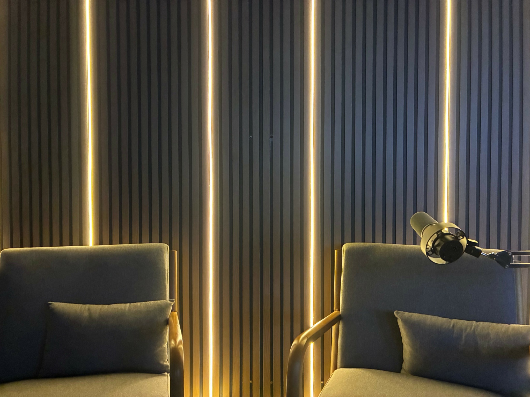 Two chairs with pillows in a room with vertical striped wall and vertical light strips.