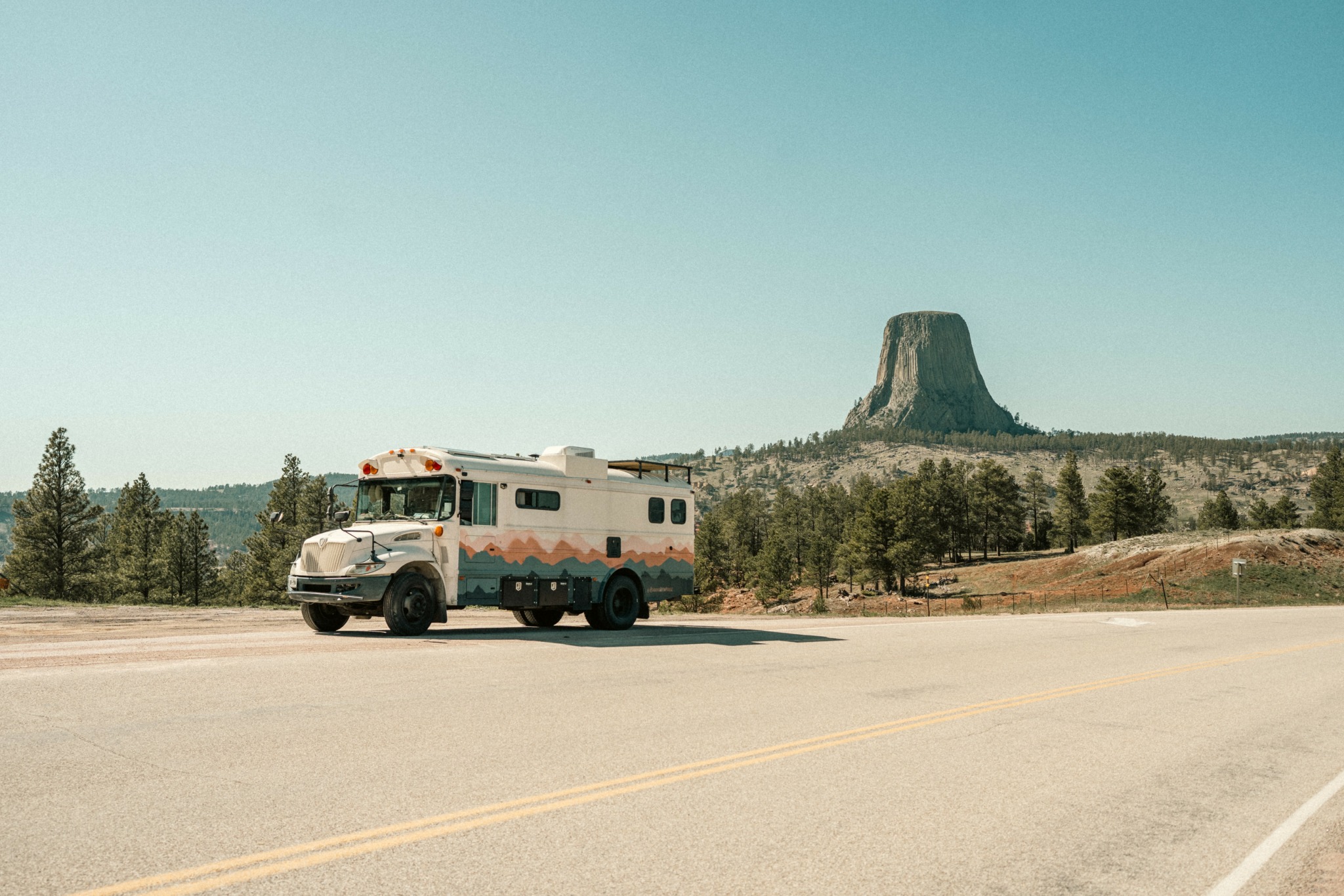 A white recreational vehicle parked on the side of a road with a flat-topped mountain in the background.
