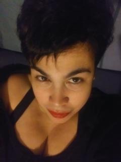 Young woman with short dark hair, wearing a black top, looking at the camera.