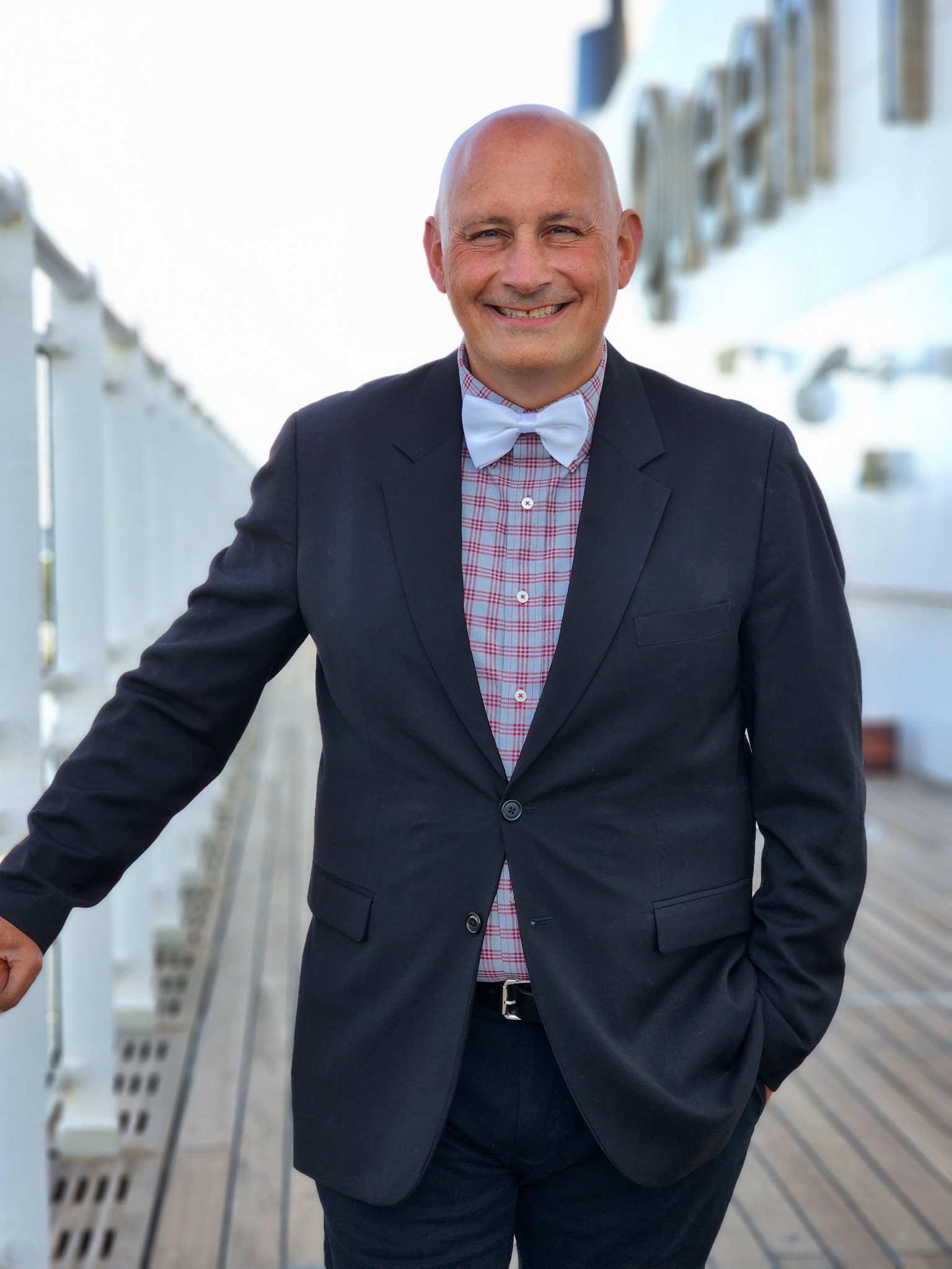 Smiling man in suit standing outdoors with a modern building background.
