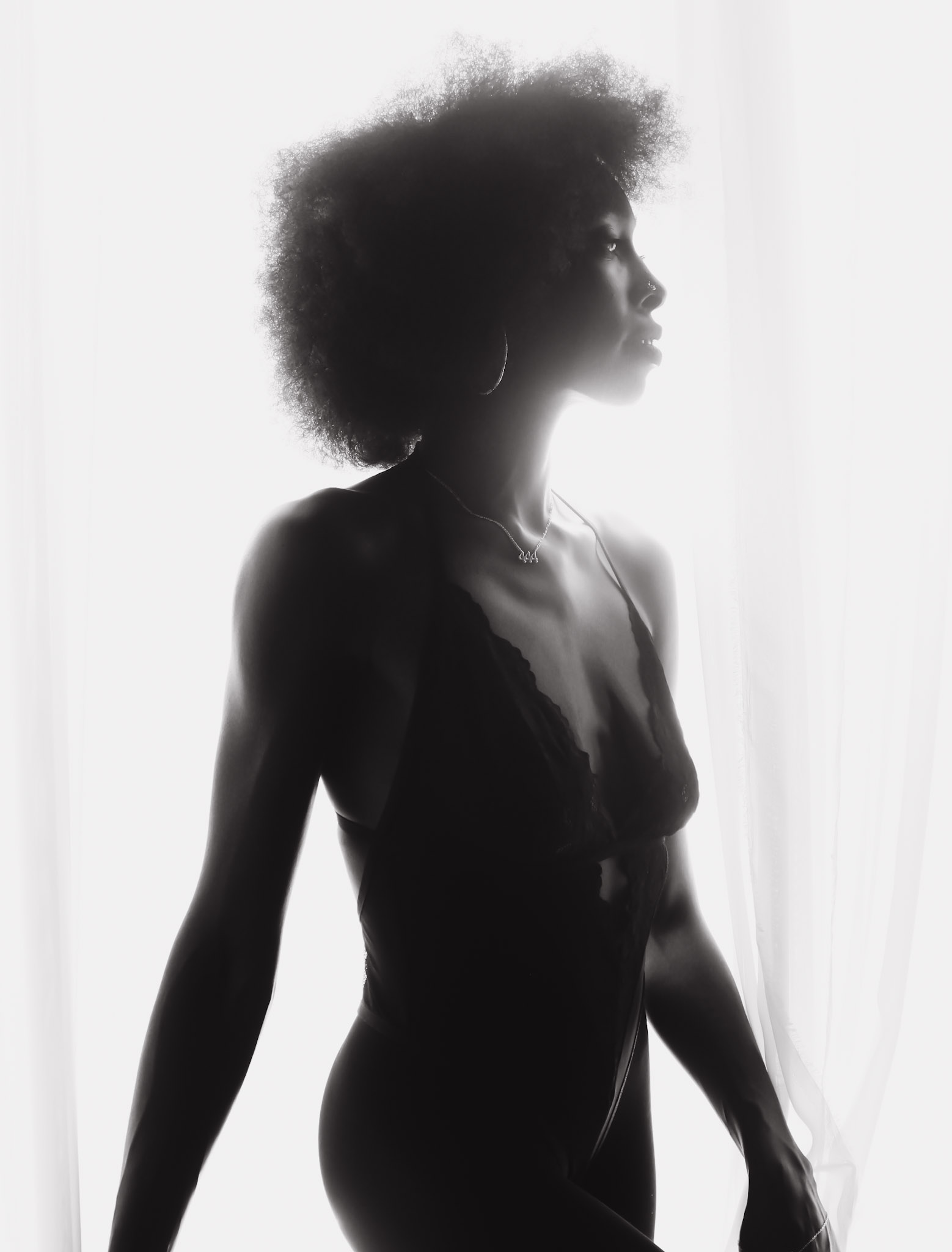Silhouette of a woman with natural hair, standing sideways with a light background.