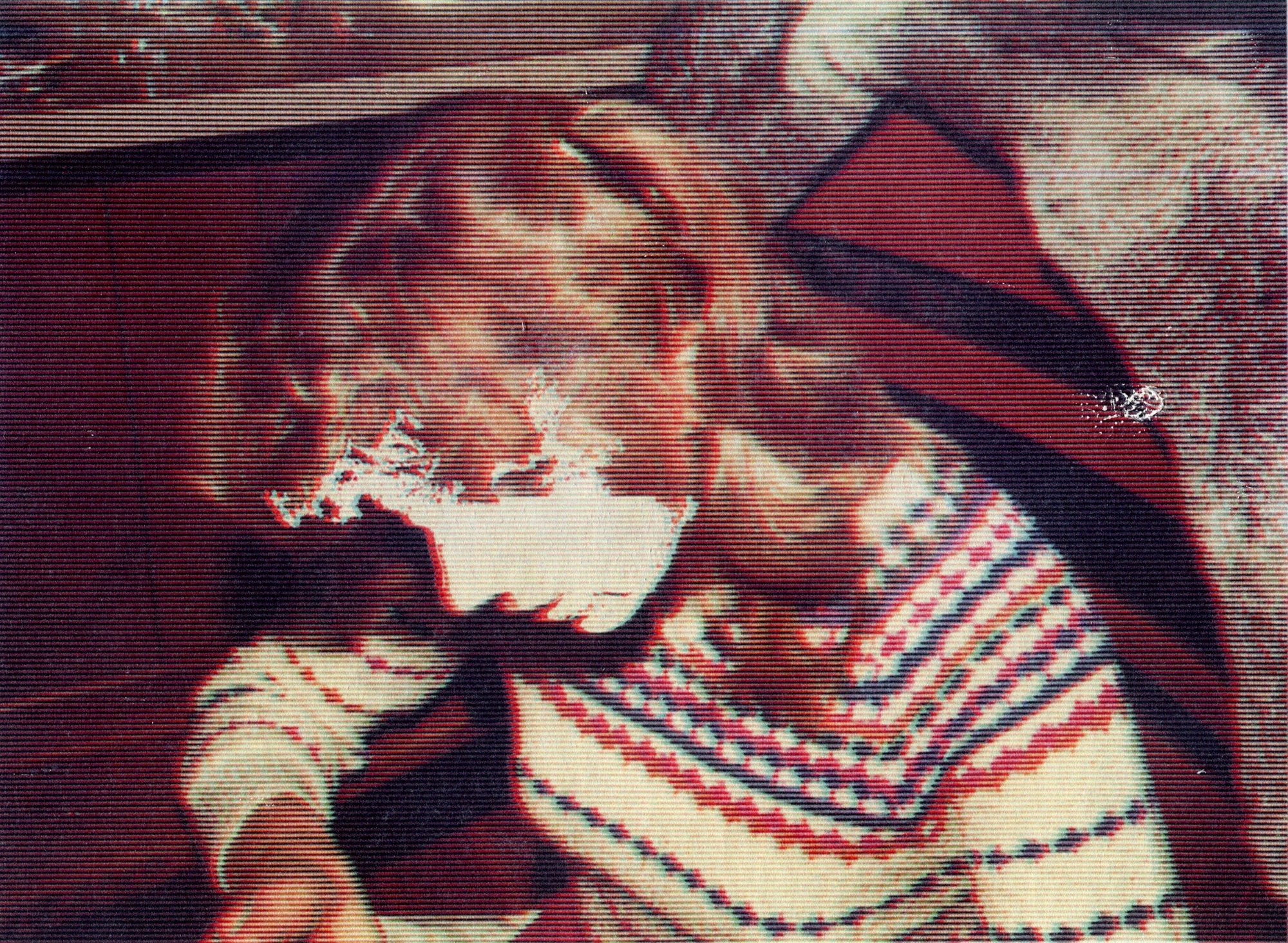 Child with curly hair wearing a patterned sweater, sitting at a table with a dark background.
