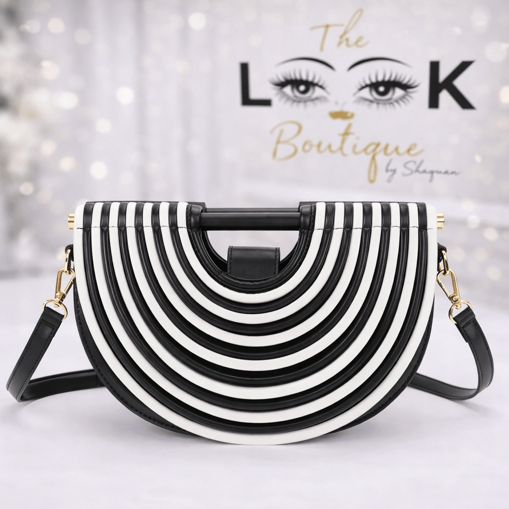 Black and white striped handbag with a curved shape and gold hardware, displayed in front of a decorative background.
