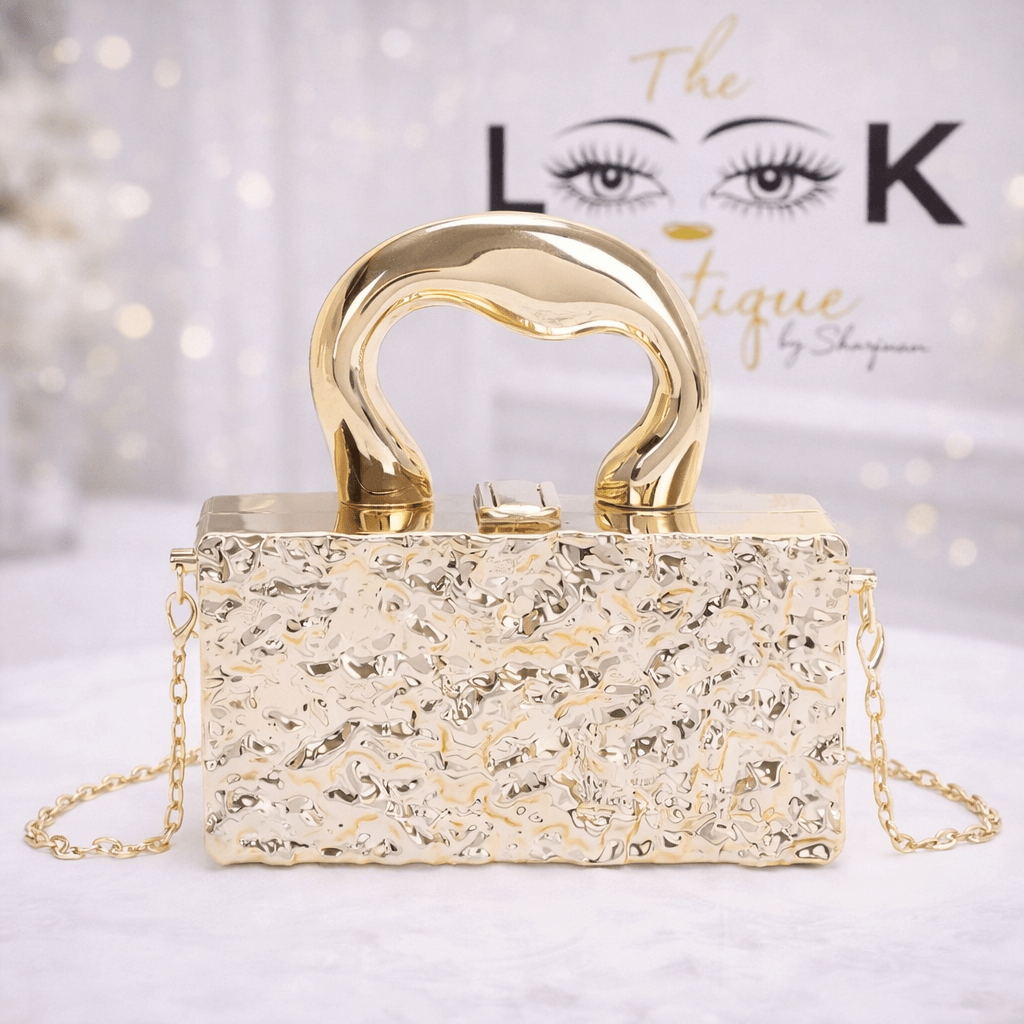 Gold textured handbag with a curved handle and chain straps on a white surface.