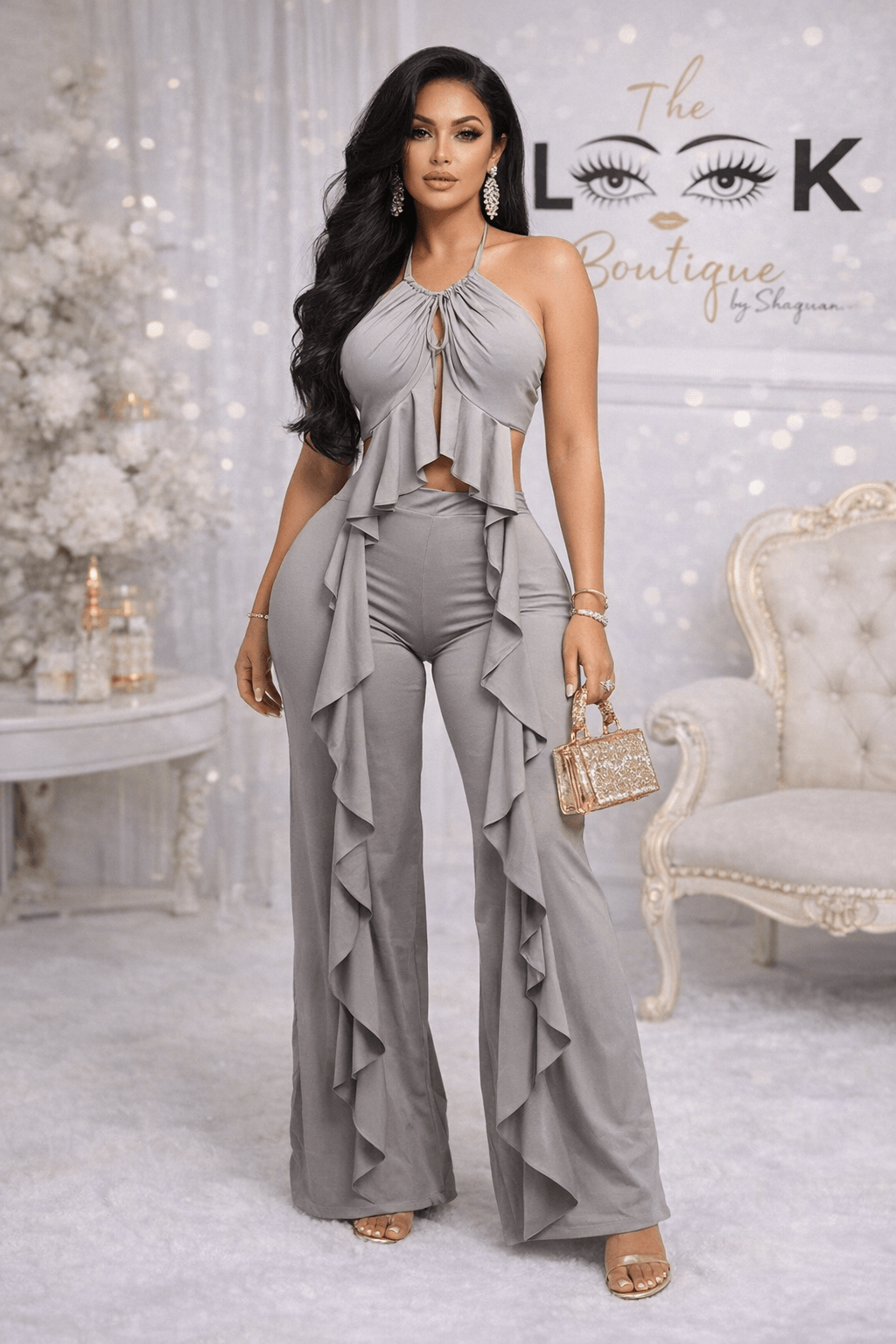Woman in gray dress with ruffles, standing indoors with white furniture and decorative background.