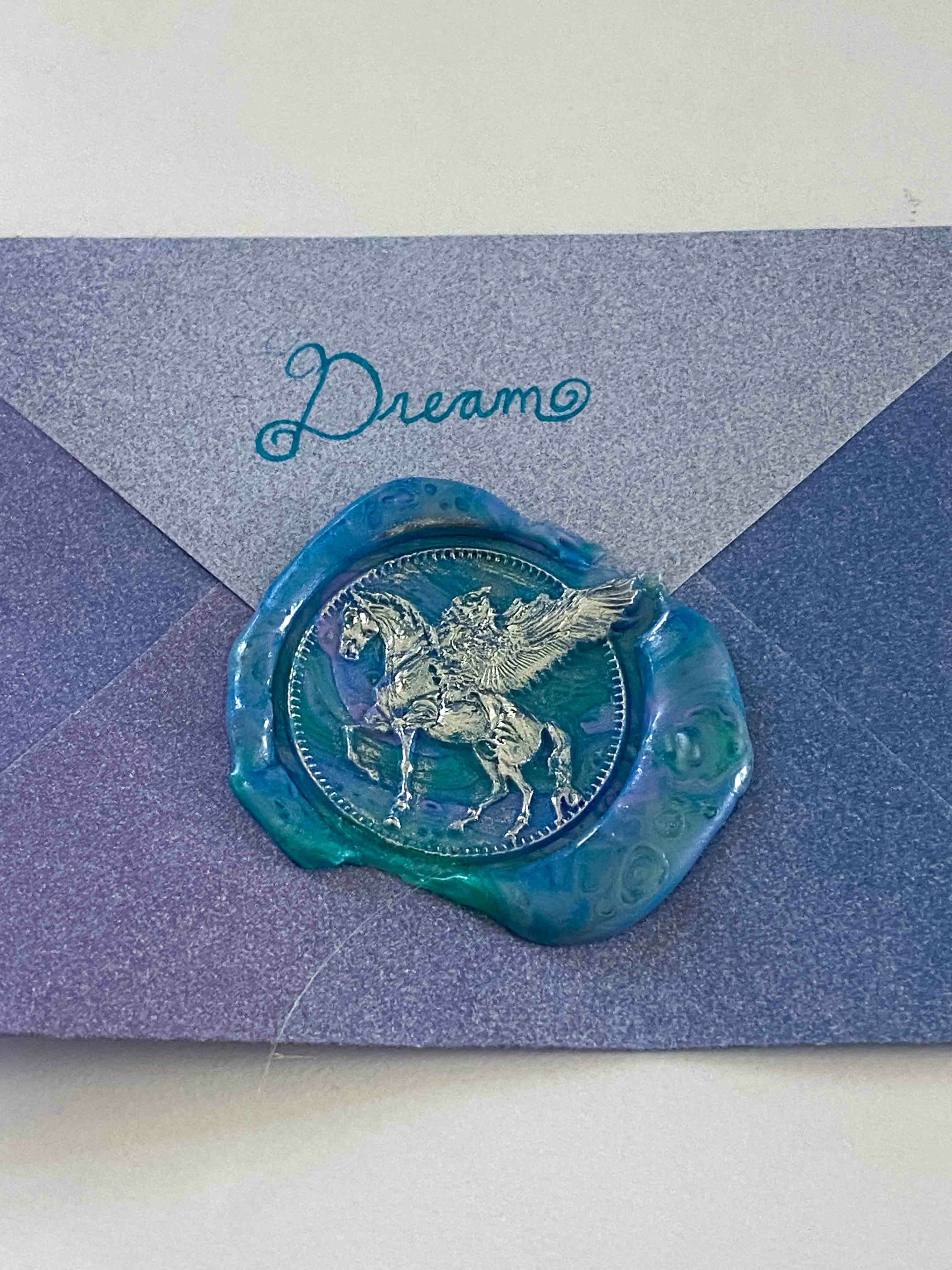 Blue wax seal with a horse and rider, placed on a purple and gray envelope with the word 'Dream' written above.