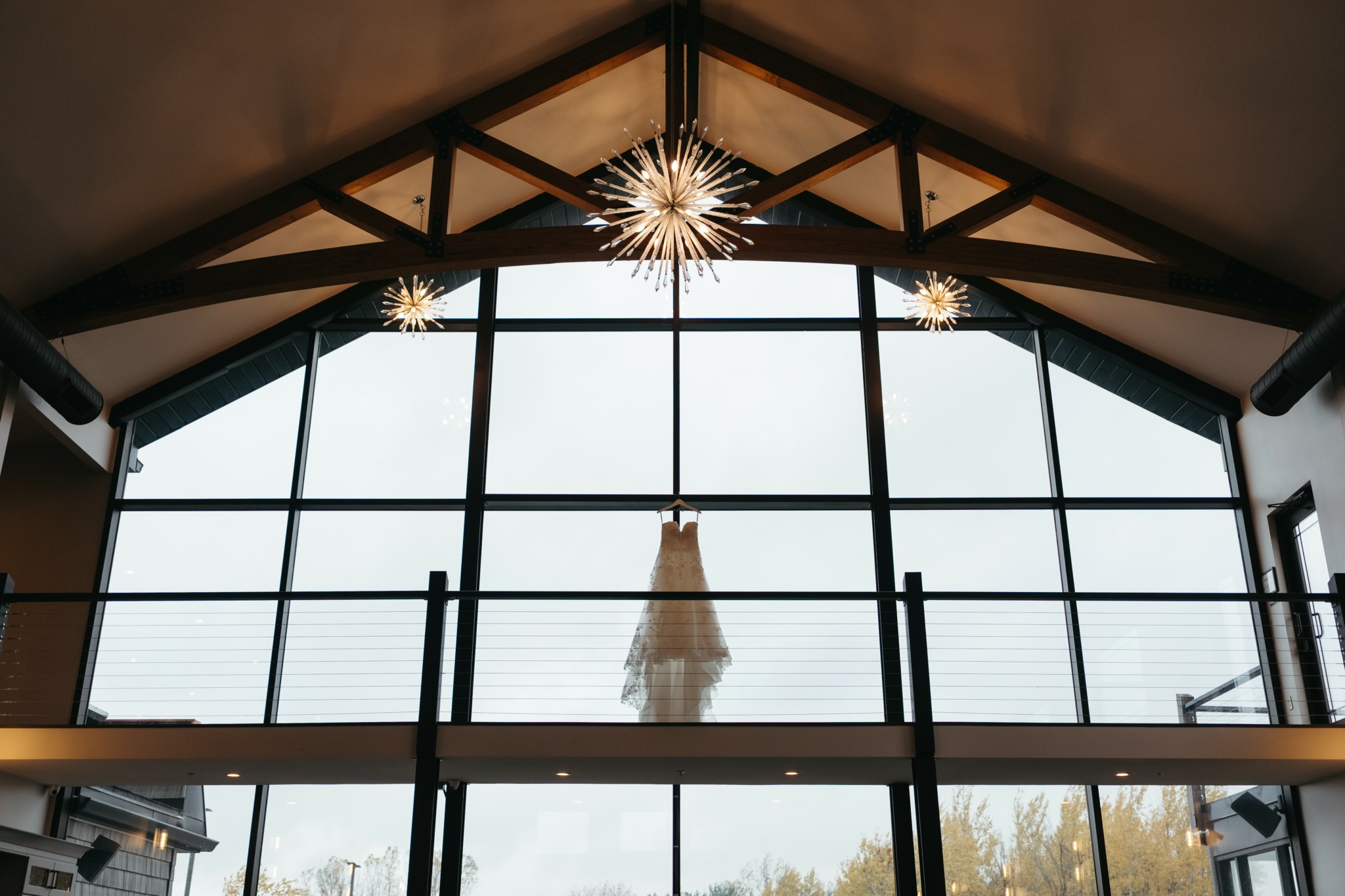 Interior view of a building with large glass windows, wooden ceiling, and hanging star-shaped lights.