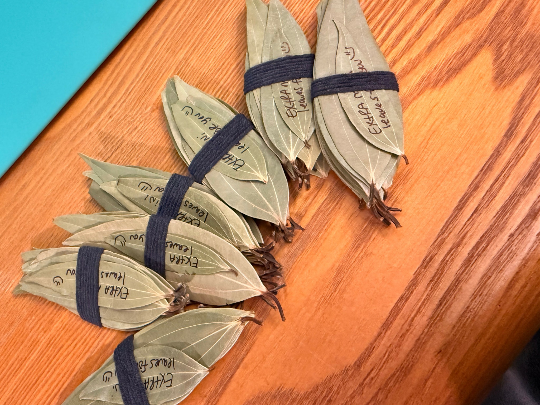 Six bundles of paper money wrapped with black rubber bands on a wooden surface.