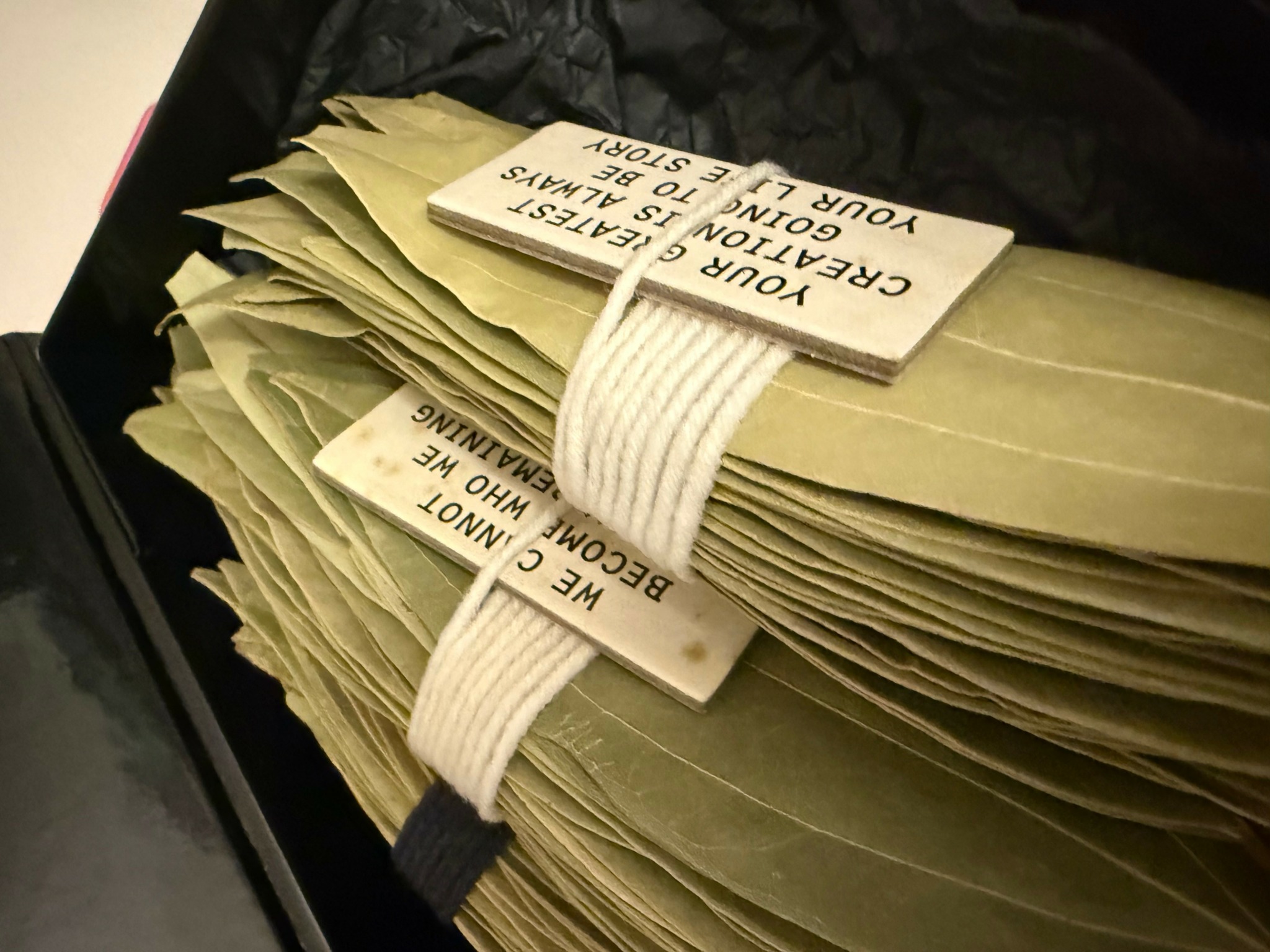 Stack of yellowed papers secured with a white elastic band, some with printed labels attached.