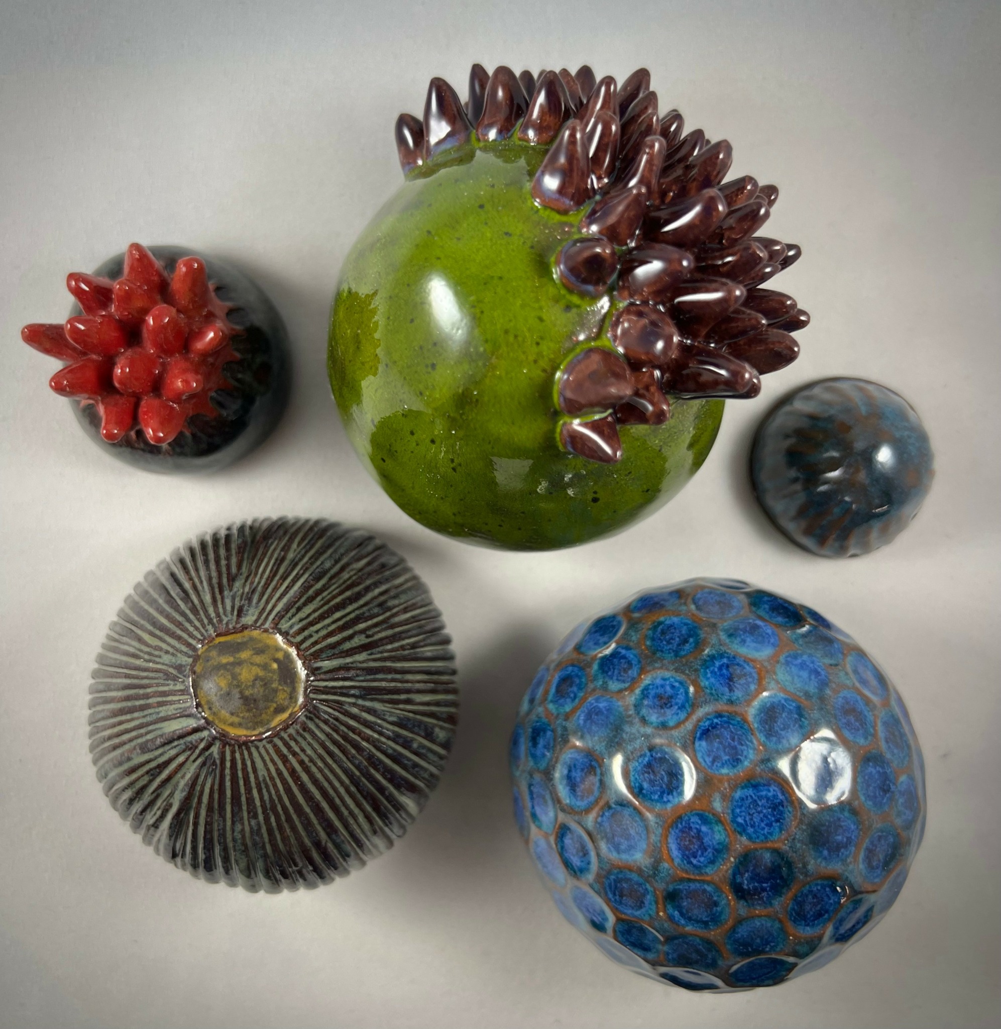 Five decorative glass orbs with various colors and patterns on a light surface.