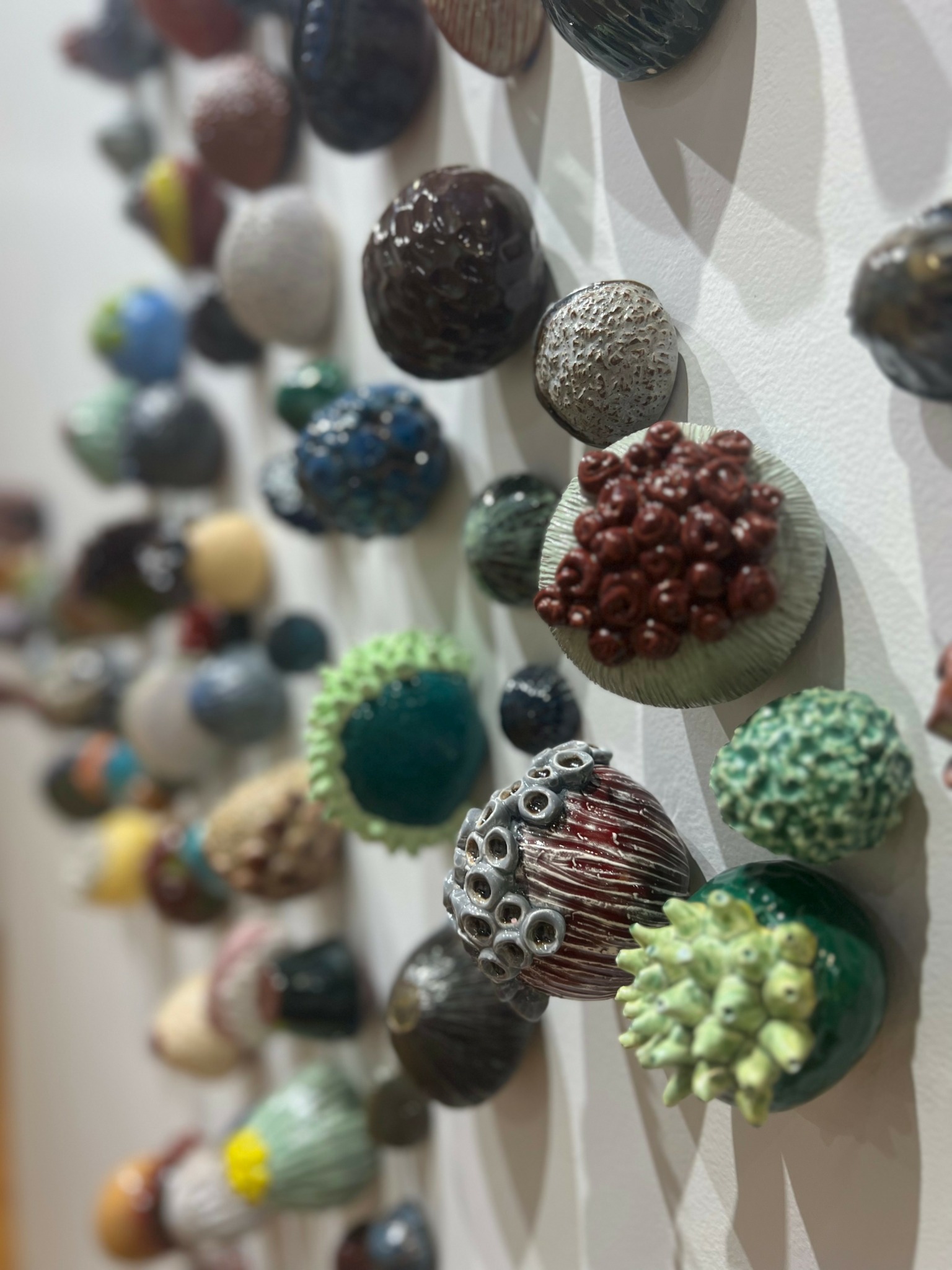 Close-up of various textured, colorful objects arranged on a white surface, some resembling small decorative balls or stones.