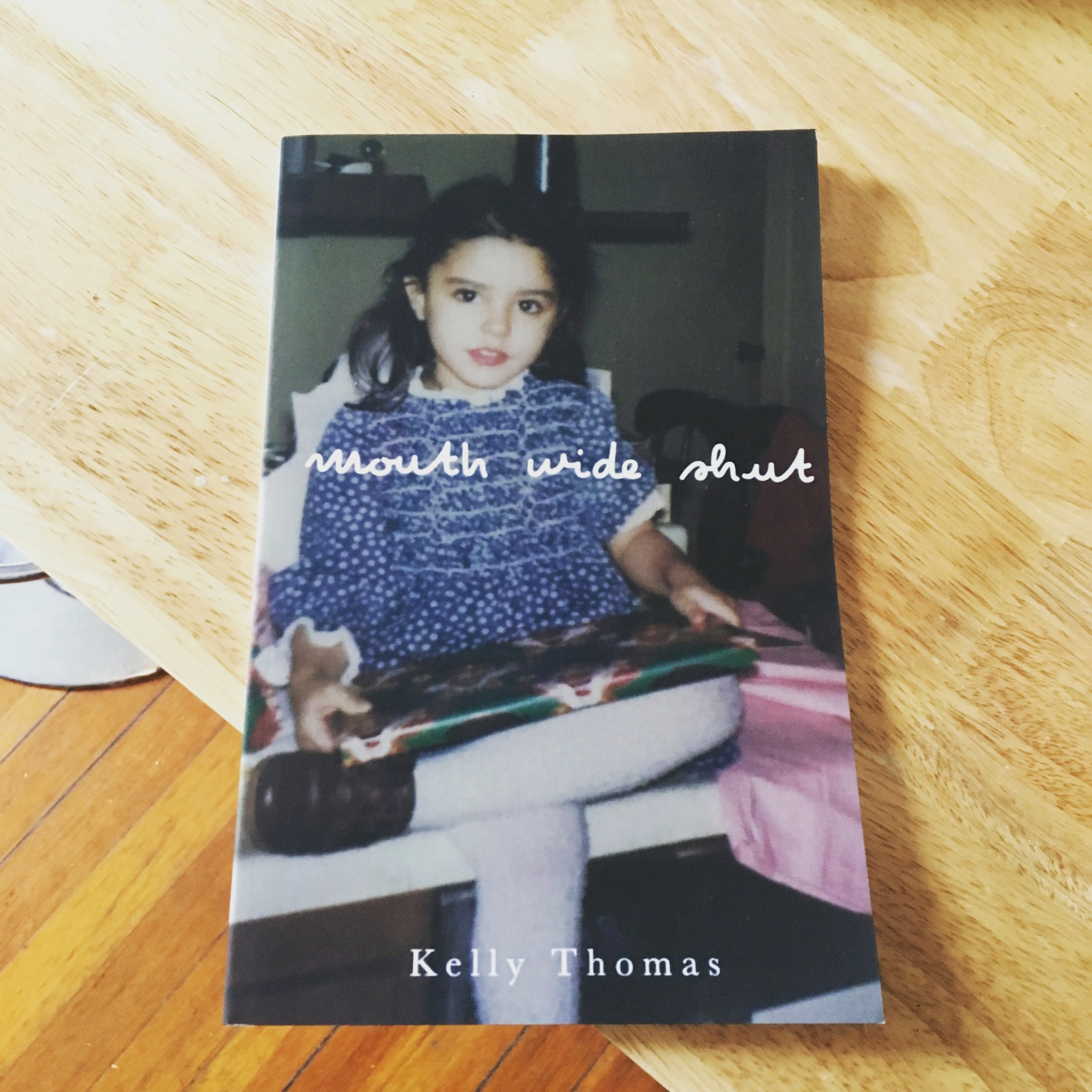 Book cover showing a girl sitting on a bench, wearing a blue dress with white polka dots, holding a book.