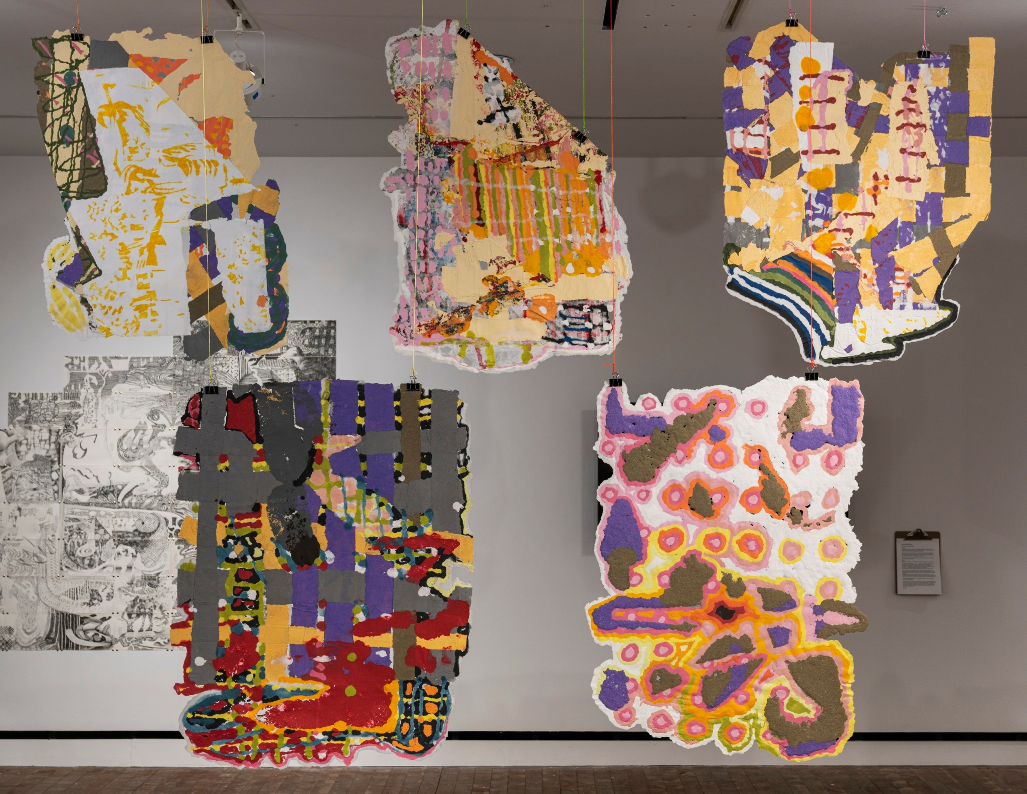 Five colorful abstract hanging sculptures with various shapes and patterns in an art gallery.