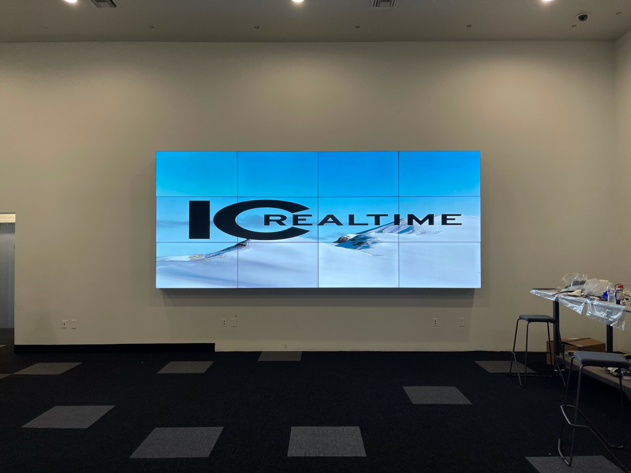 Large digital screen displaying a logo with the text 'IC REALTIME' on a plain wall.