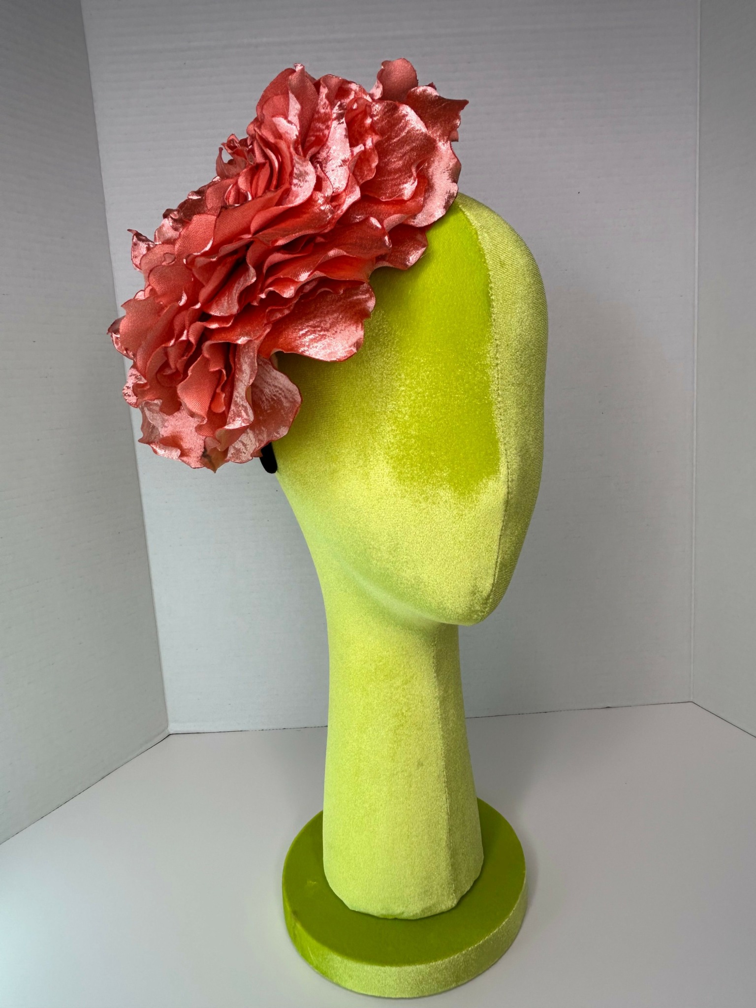 Green vegetable with a pink ruffled flower-like top, placed on a white surface and corner.