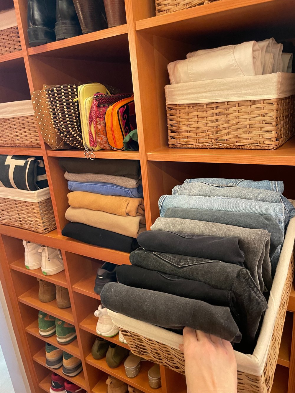 Shelves with folded towels, baskets, and shoes in a closet or storage area.