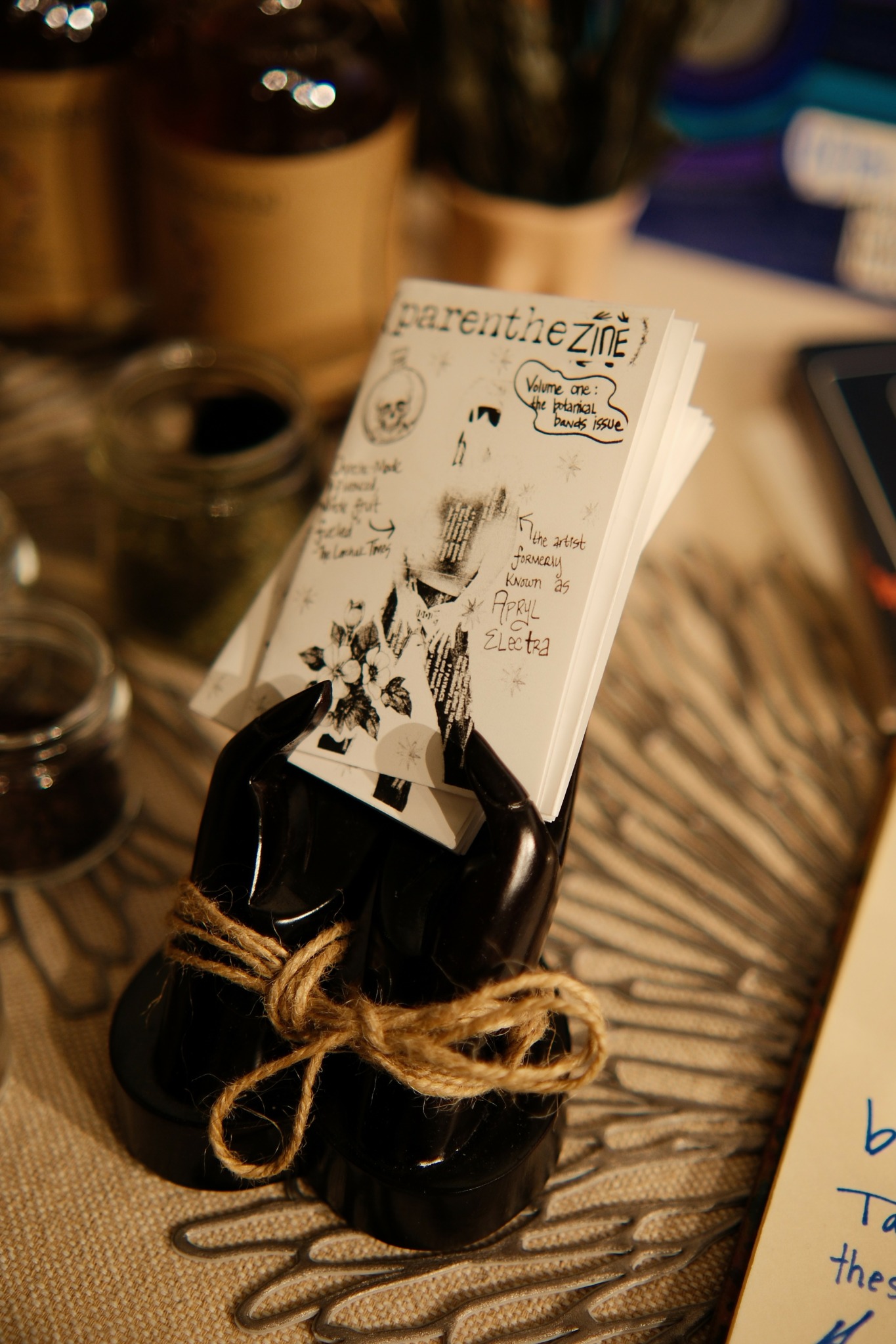 Black container holding business cards with a handwritten note on top, tied with a rope, on a patterned surface.