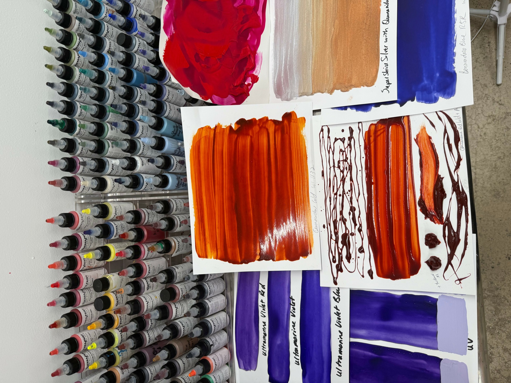 Paint swatches and brushes on a table with various colors including red, orange, purple, and blue.