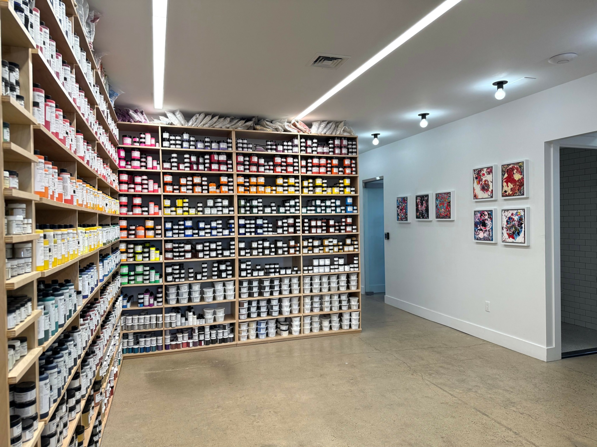 Store interior with shelves filled with colorful products, white walls, and framed artwork on the wall.