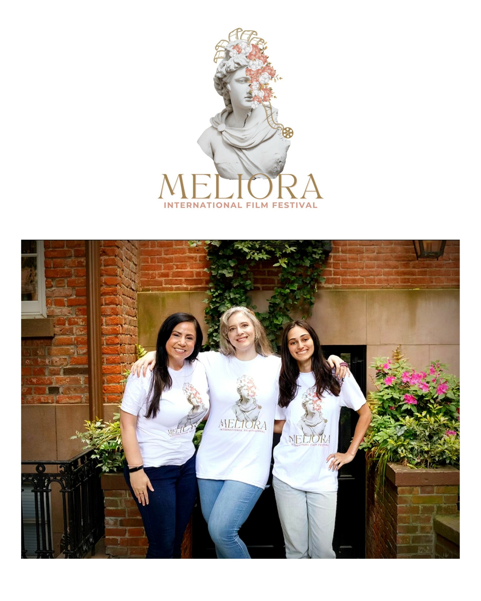 Three women stand outdoors in front of a brick wall and greenery, smiling and wearing matching Meliora T-shirts.
