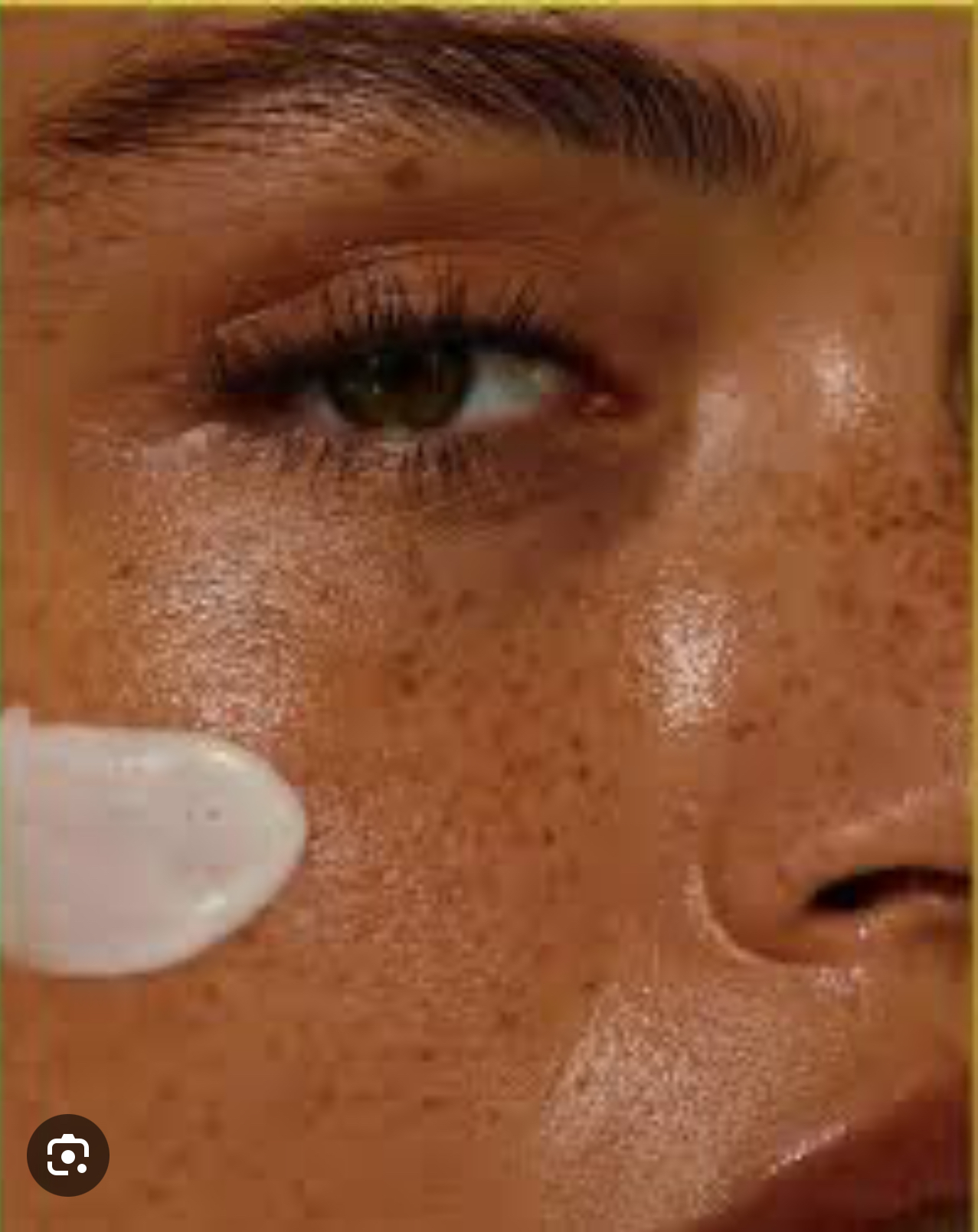 Close-up of a person's face showing eye, eyebrow, and freckles, with a white object partially visible.