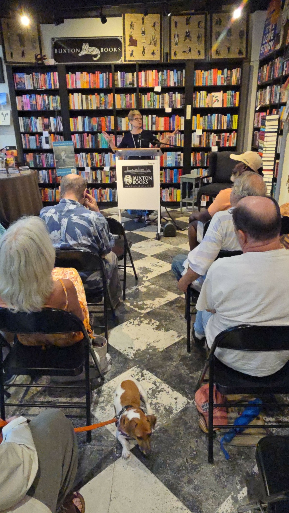 People sitting at tables in a bookstore or library with shelves of books in the background.