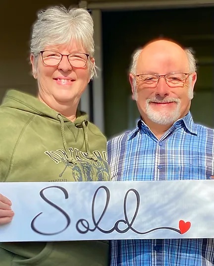 Two smiling people holding a sign that says 