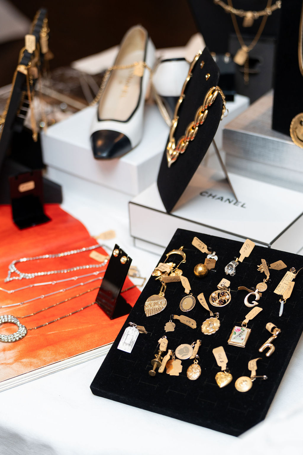 Jewelry display with gold necklaces, earrings, and rings on black and white stands, and a red fabric surface with additional jewelry.
