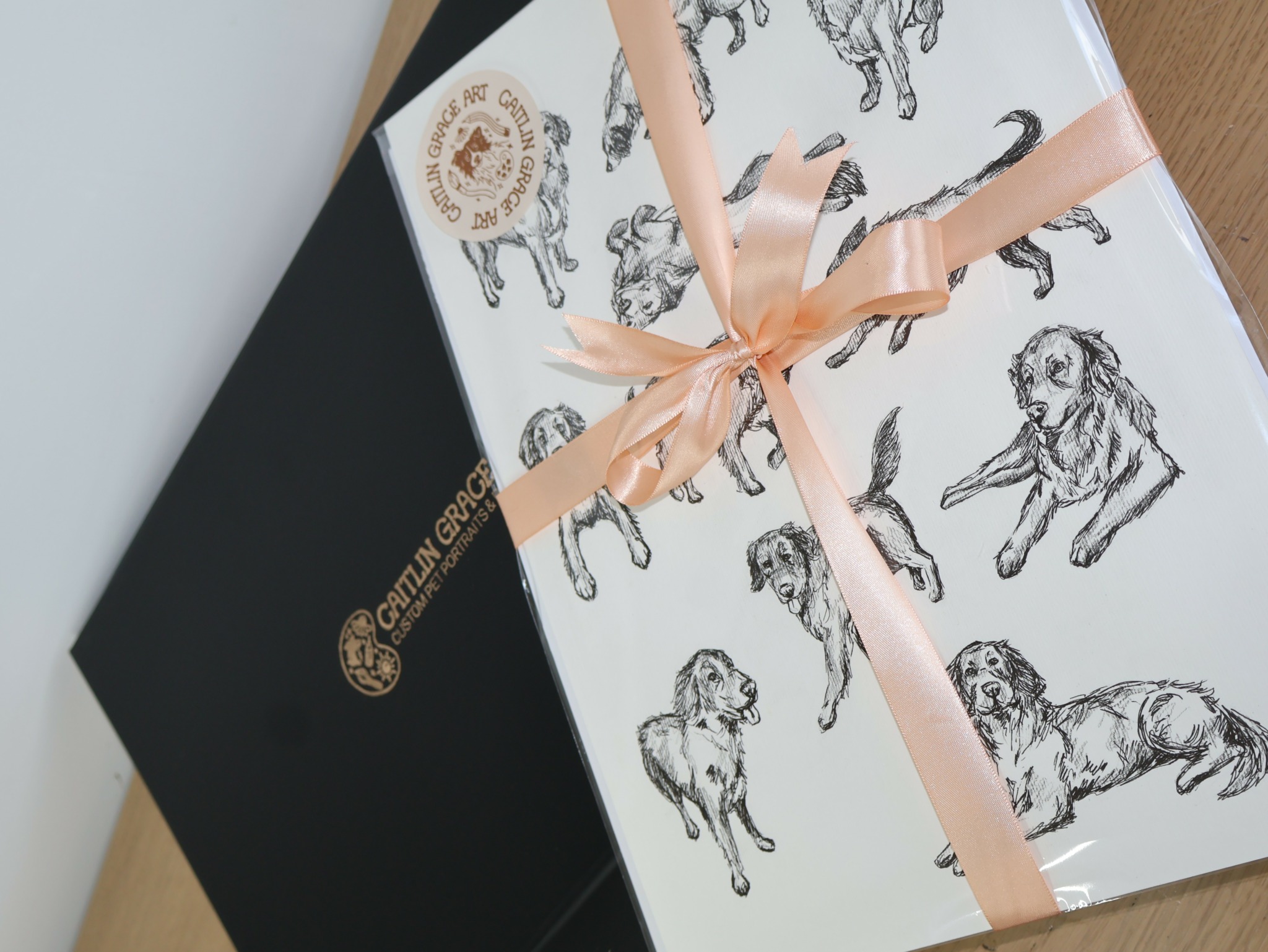 Gift box wrapped with ribbon, decorated with sketches of dogs, on a wooden surface.