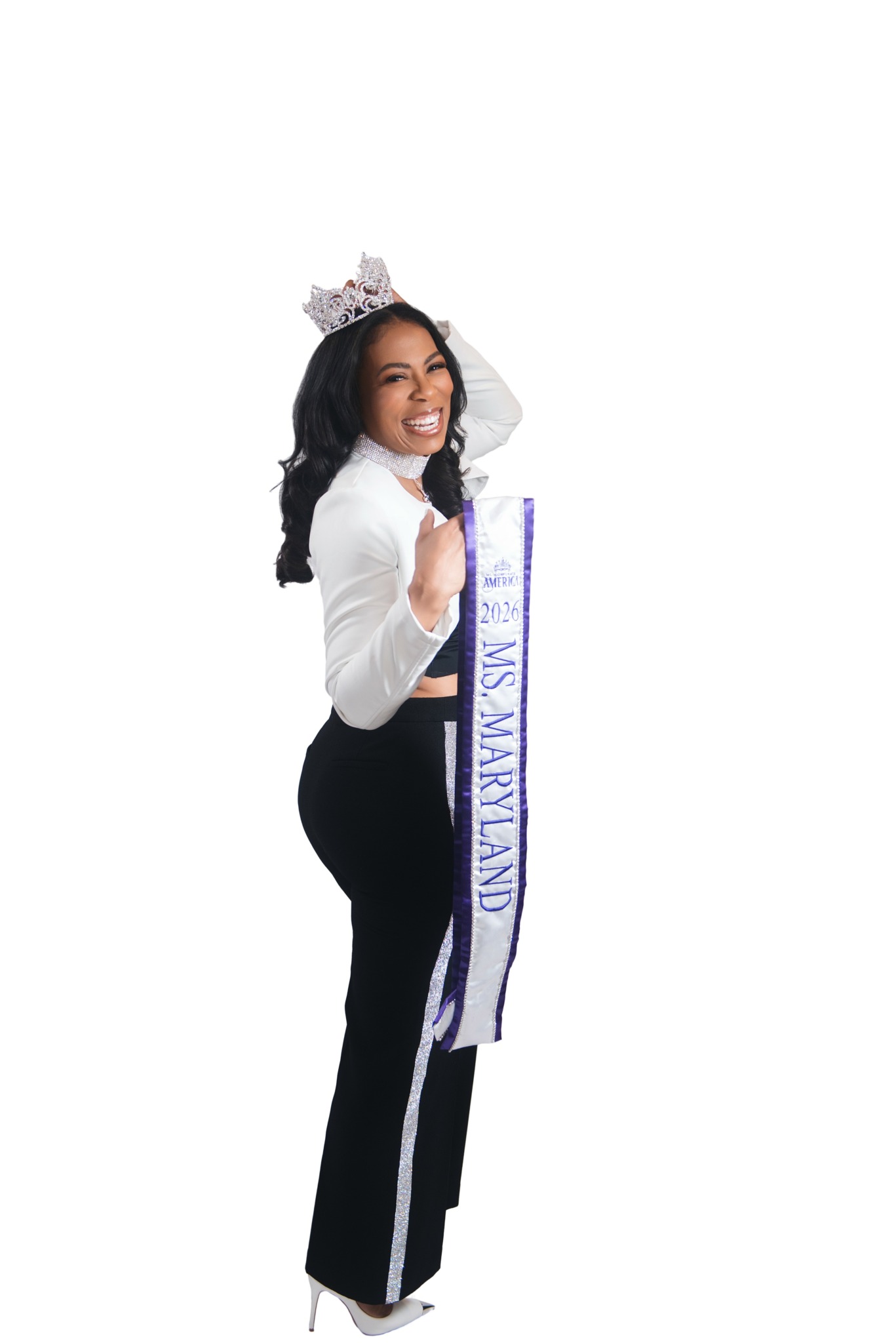 Woman smiling, wearing a sash and crown, holding a bouquet, standing in profile against a white background.