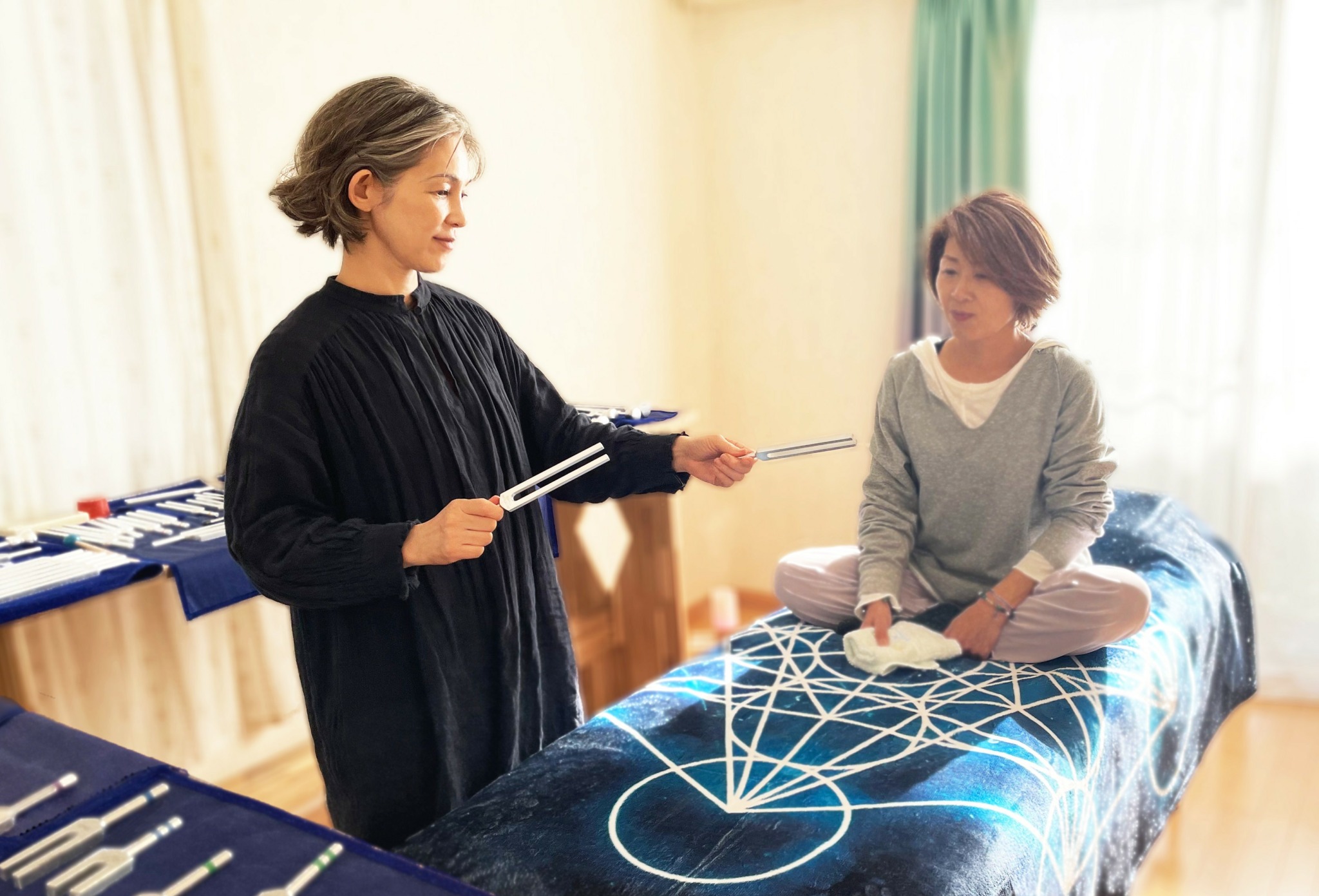 Woman and child interact with holographic projection on bed in room with curtains and sunlight.