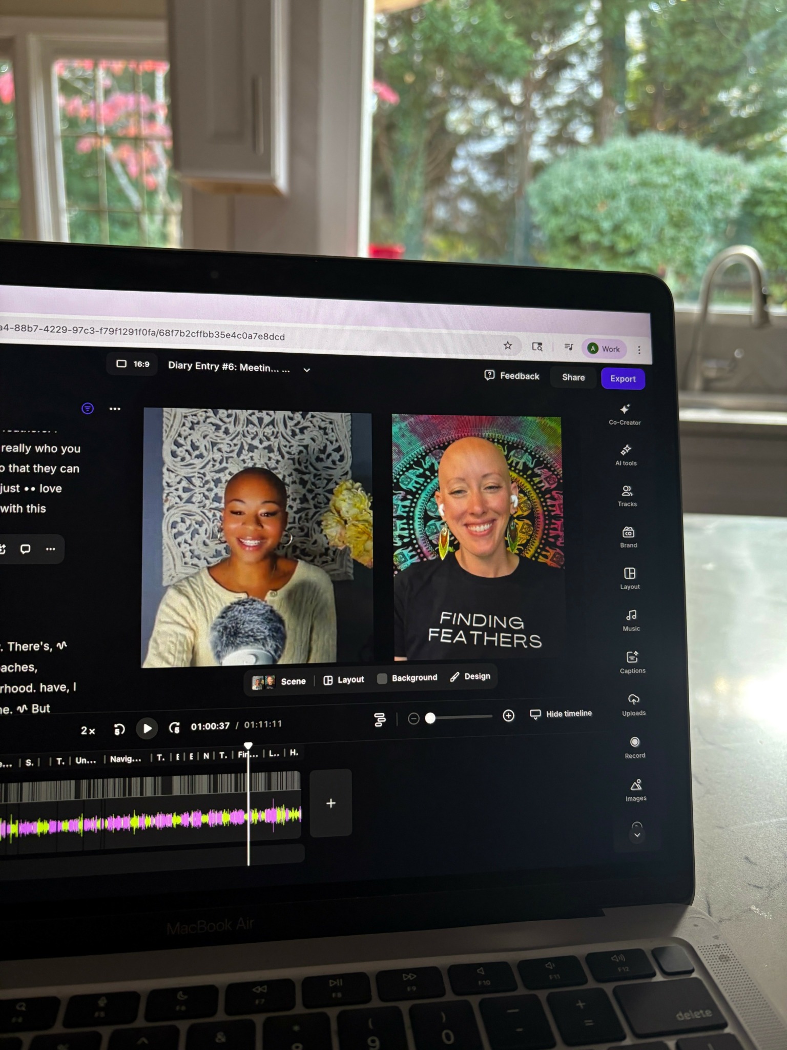 Laptop screen showing two women smiling in a video call, with a window and greenery outside in the background.