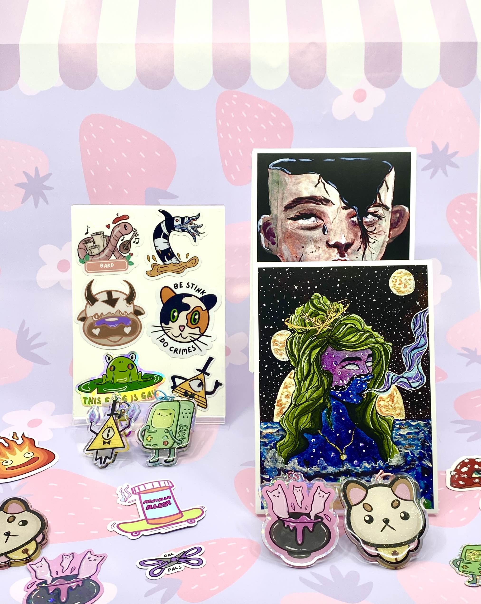 Display of colorful stickers and artwork on a pink background with strawberries and stars, including a girl with green hair and a frog.