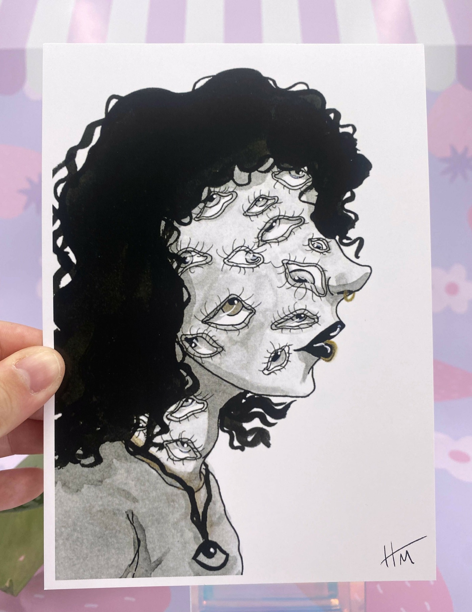 Black and white illustration of a woman with curly hair and multiple eyes on her face, with a signature in the bottom right.