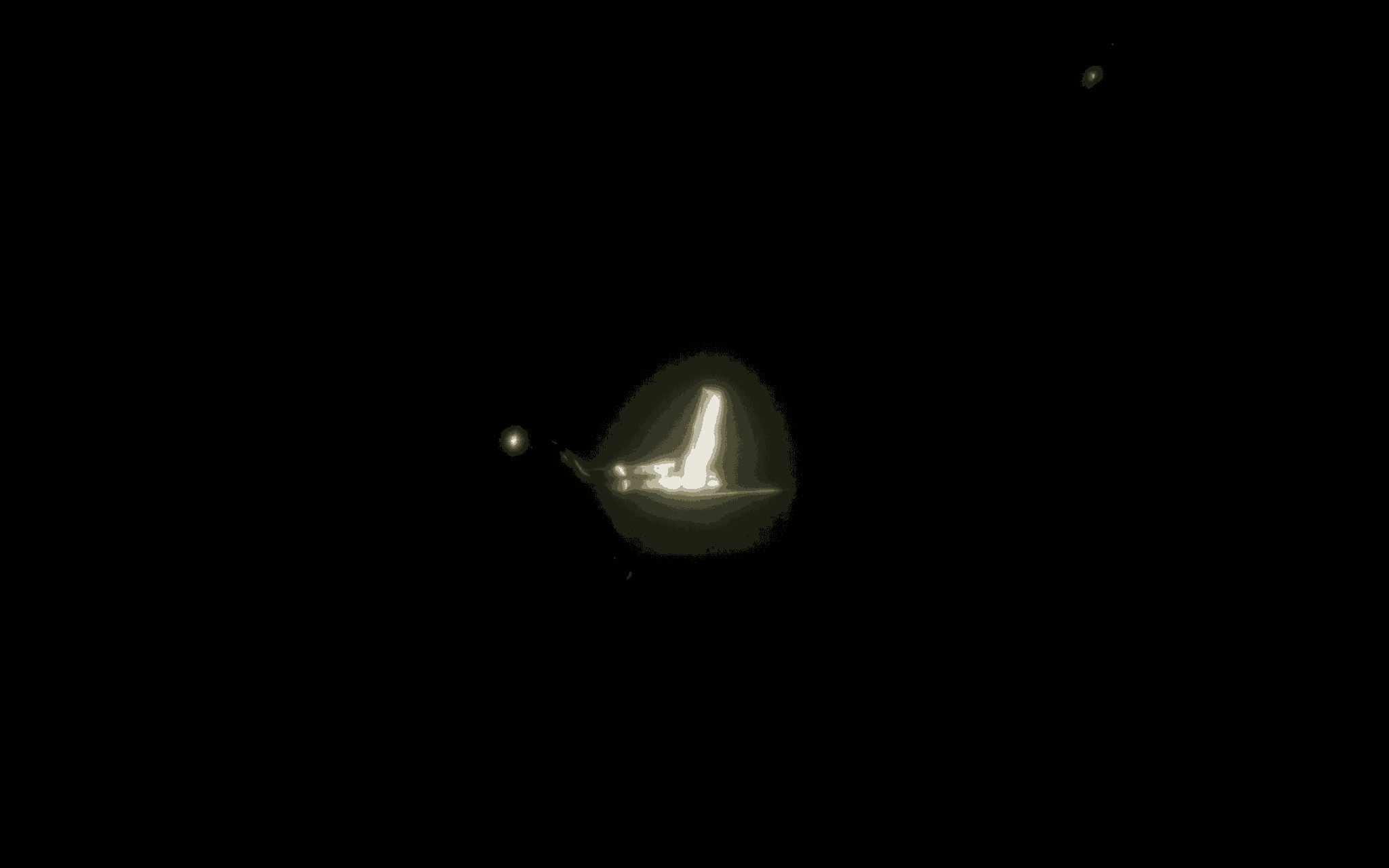 Bright light source on a dark background, with smaller lights nearby, possibly a boat or structure at night.