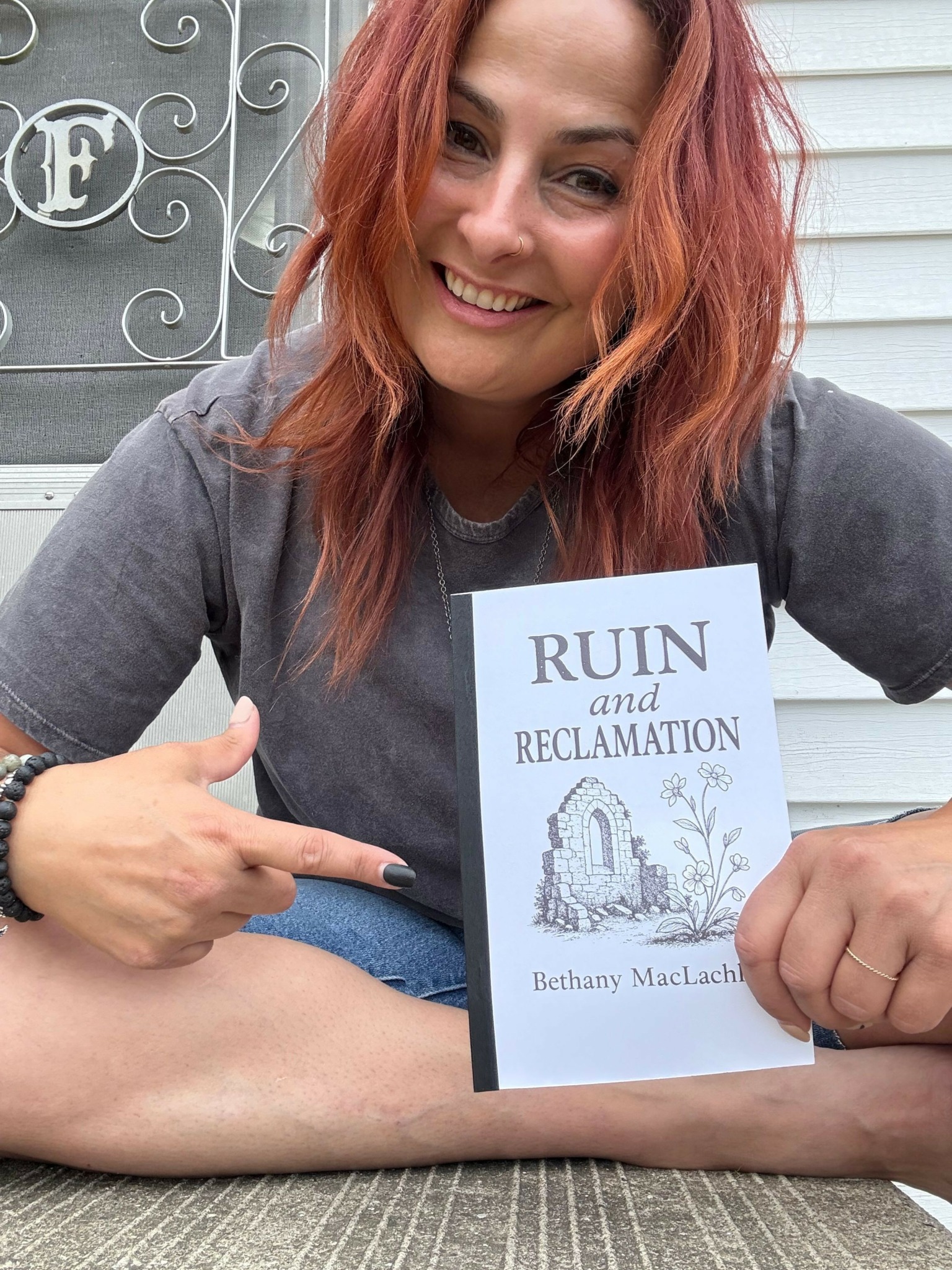 Woman with red hair smiling, holding a book titled 'RUN Registration' and pointing at it.