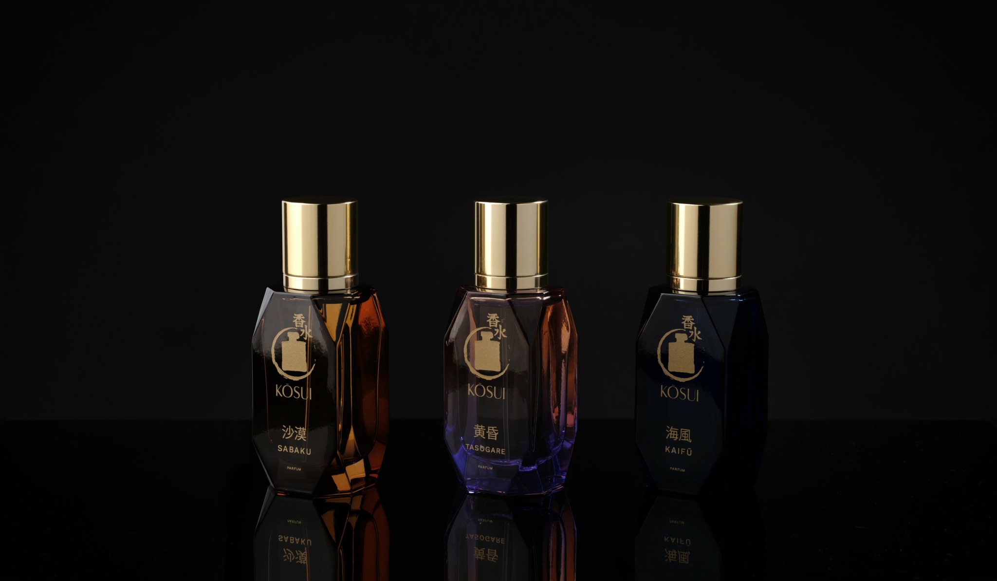 Three perfume bottles with gold caps on a reflective black surface, dark background, different colored liquids inside.