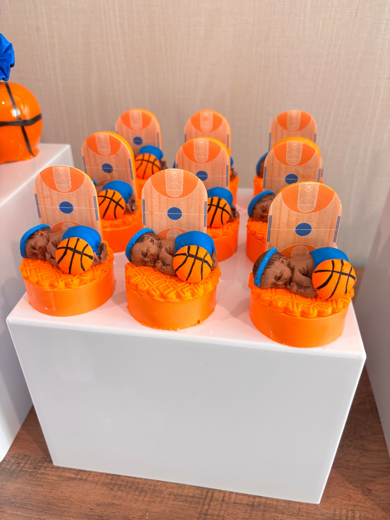 Cupcakes with basketball-themed toppers on a white tray, on a wooden surface.