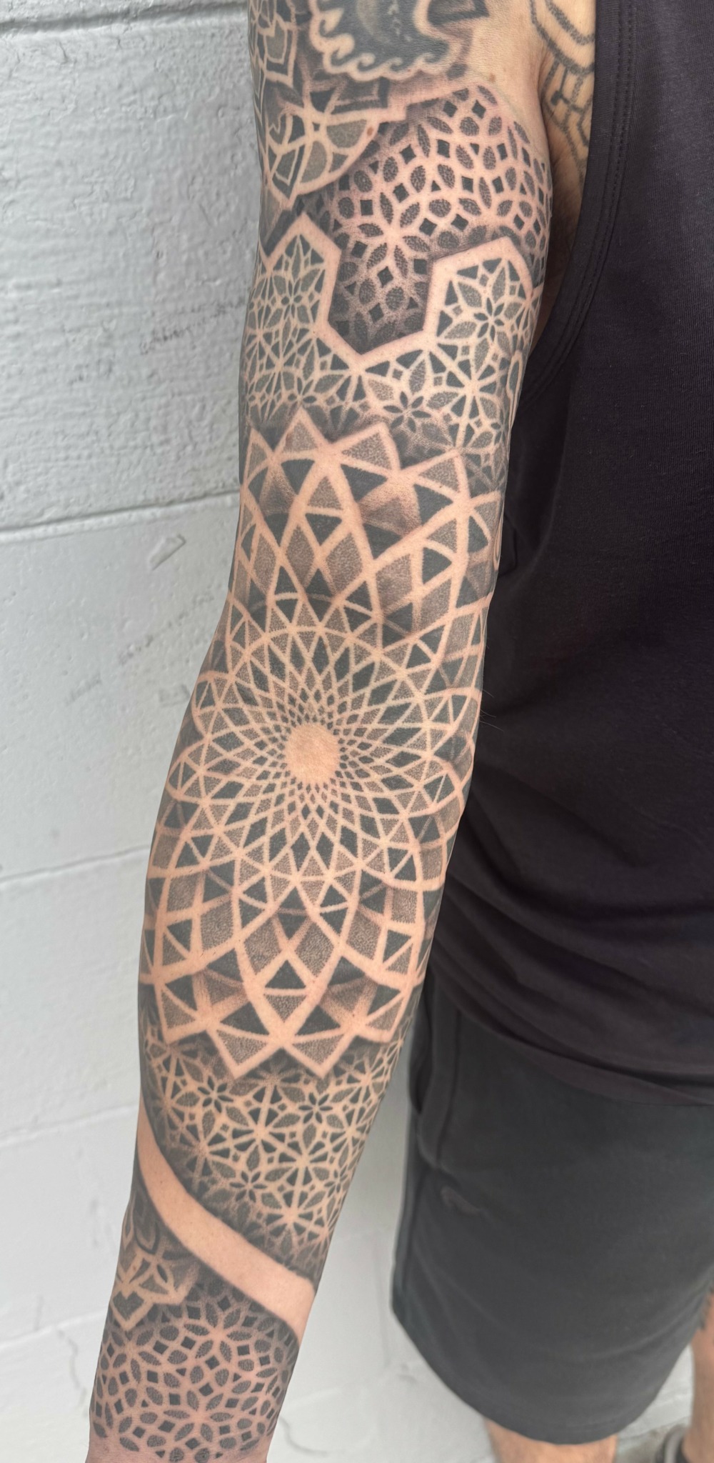 Arm with geometric tattoo design including patterns and shapes covering the entire arm.
