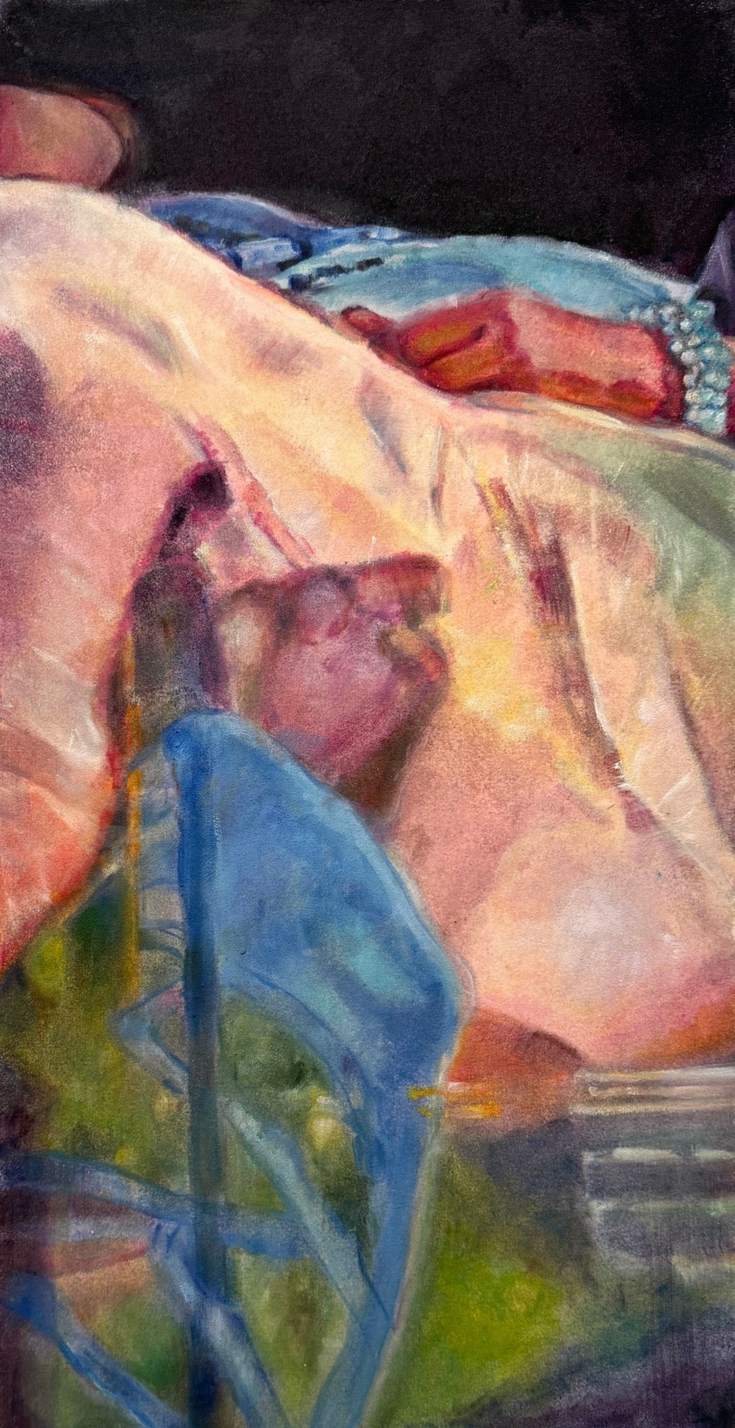 Close-up of a person lying down with a blanket, showing part of their face and shoulder, in a colorful setting.
