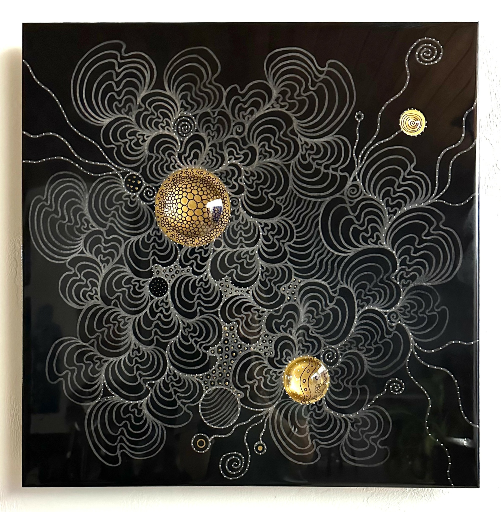 Black background with intricate white swirling lines and three gold-colored spherical objects.