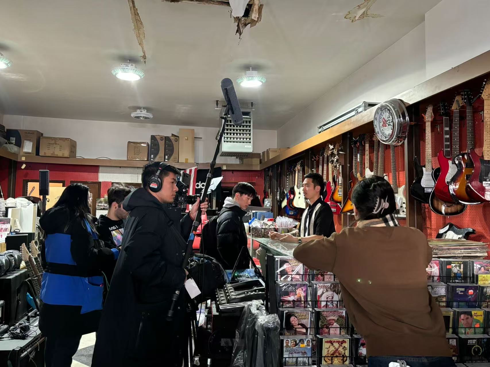 People inside a music store with guitars hanging on the wall and shelves filled with music accessories.