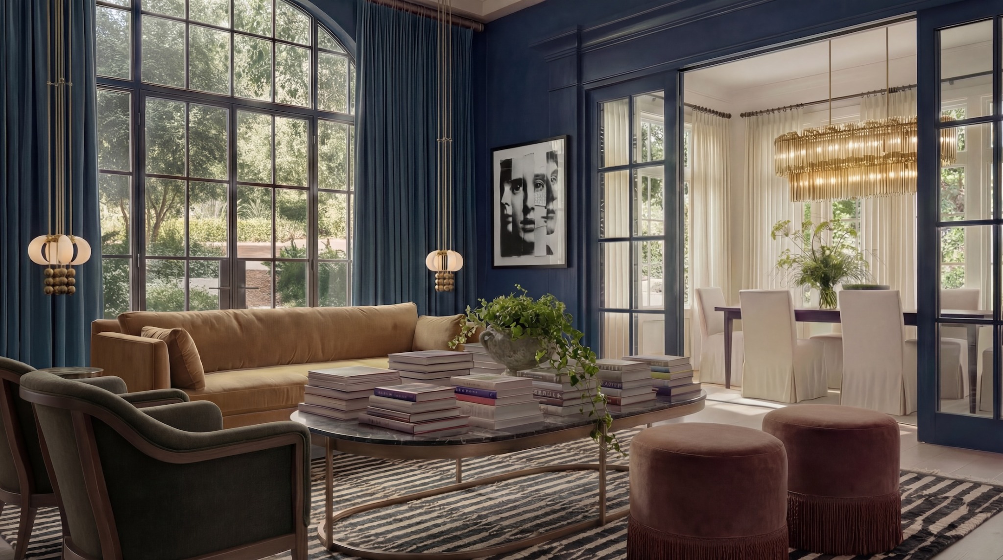 Living room with large windows, blue walls, brown sofa, armchair, and a coffee table with stacked books and plants.