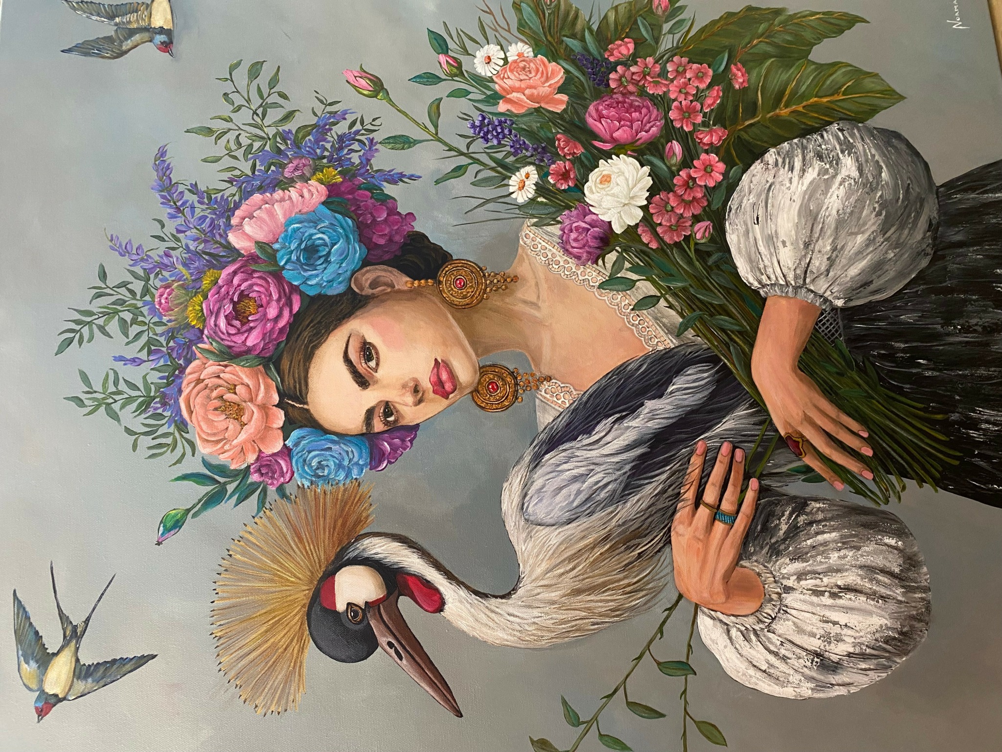 Woman with floral headdress, large earrings, and a white and black dress, holding a stork with a long beak and feathers.